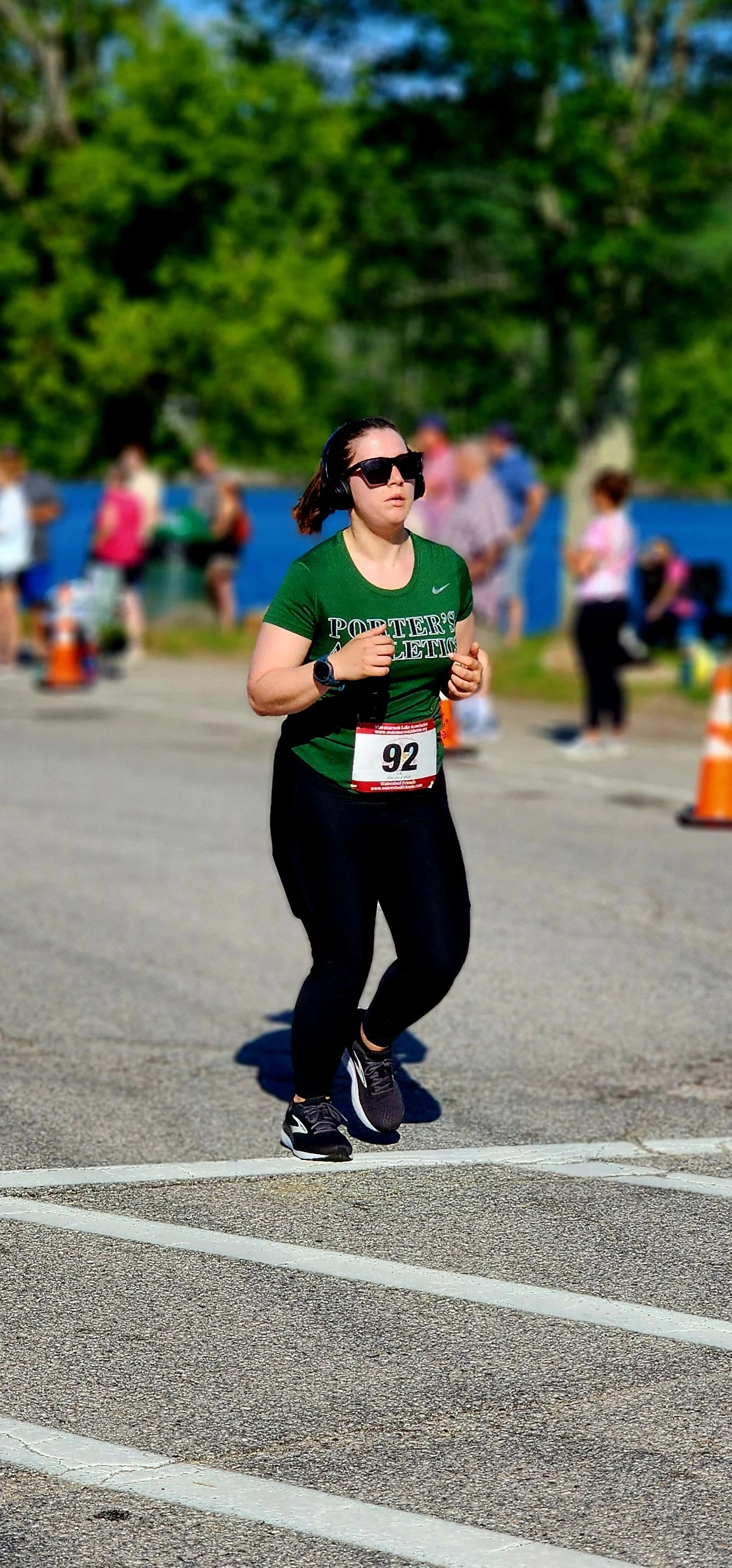 A woman wearing a green t-shirt and black leggings running