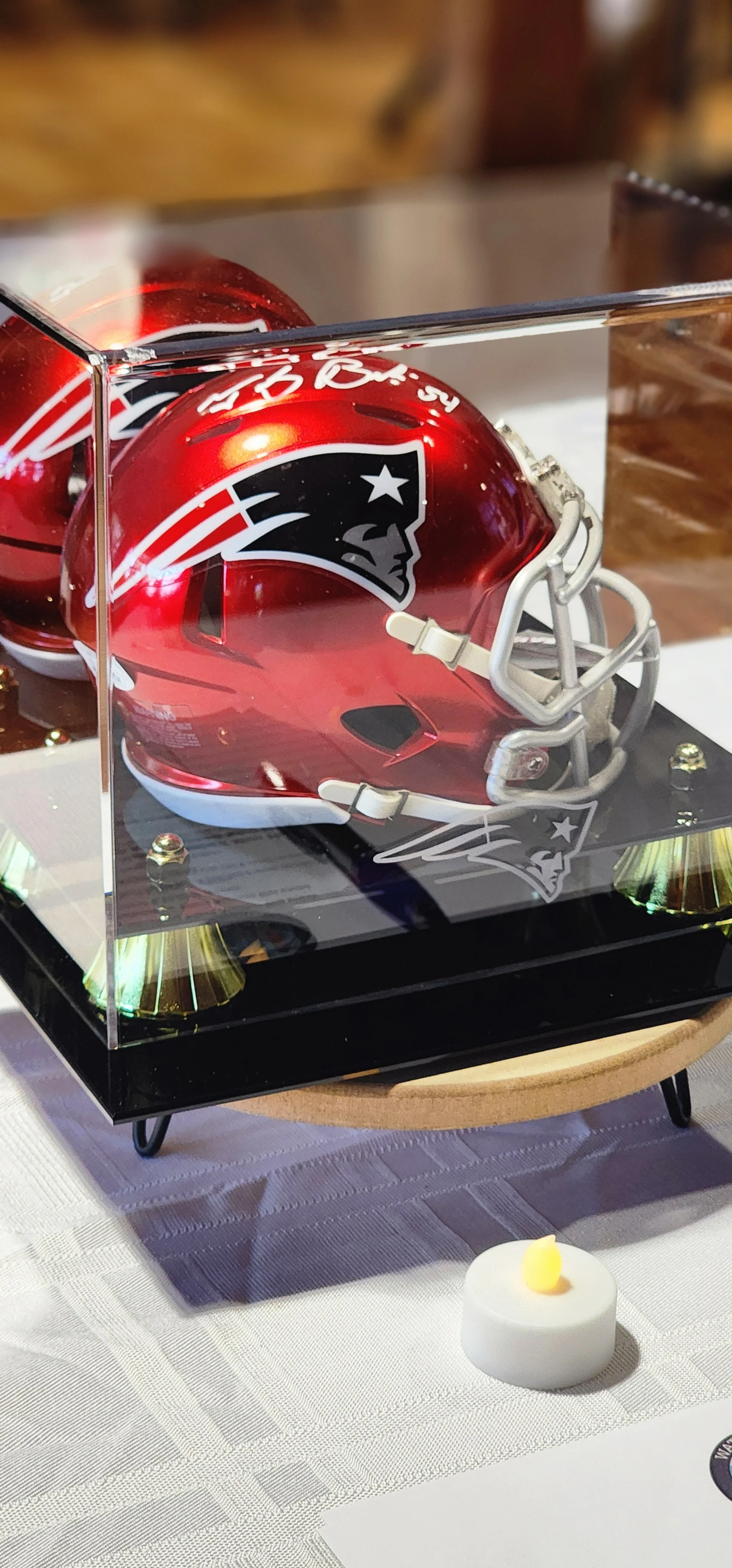 A red New England Patriots decorative helmet in a glass case