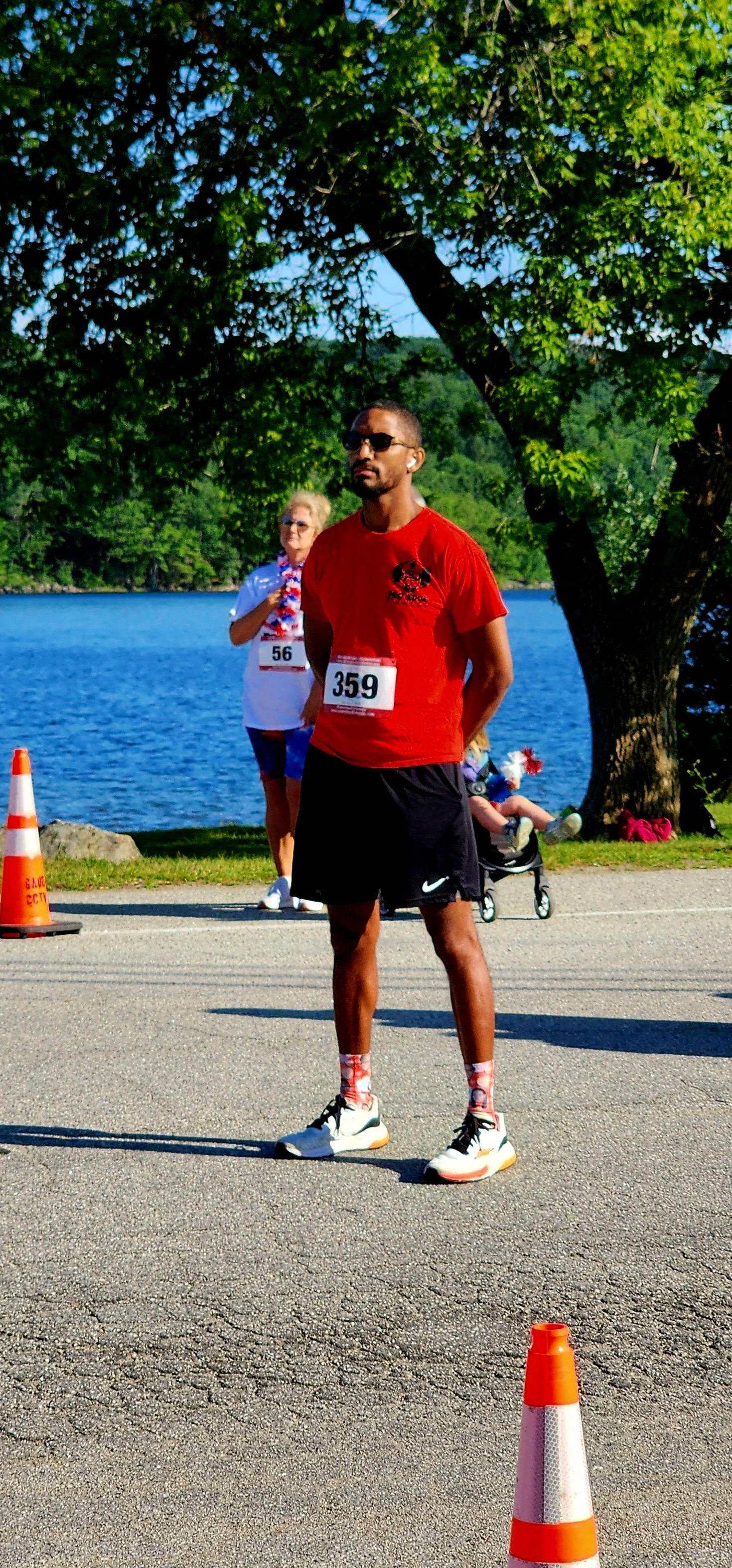 A man in a red t-shirt and black shorts, holding his hands behind his back