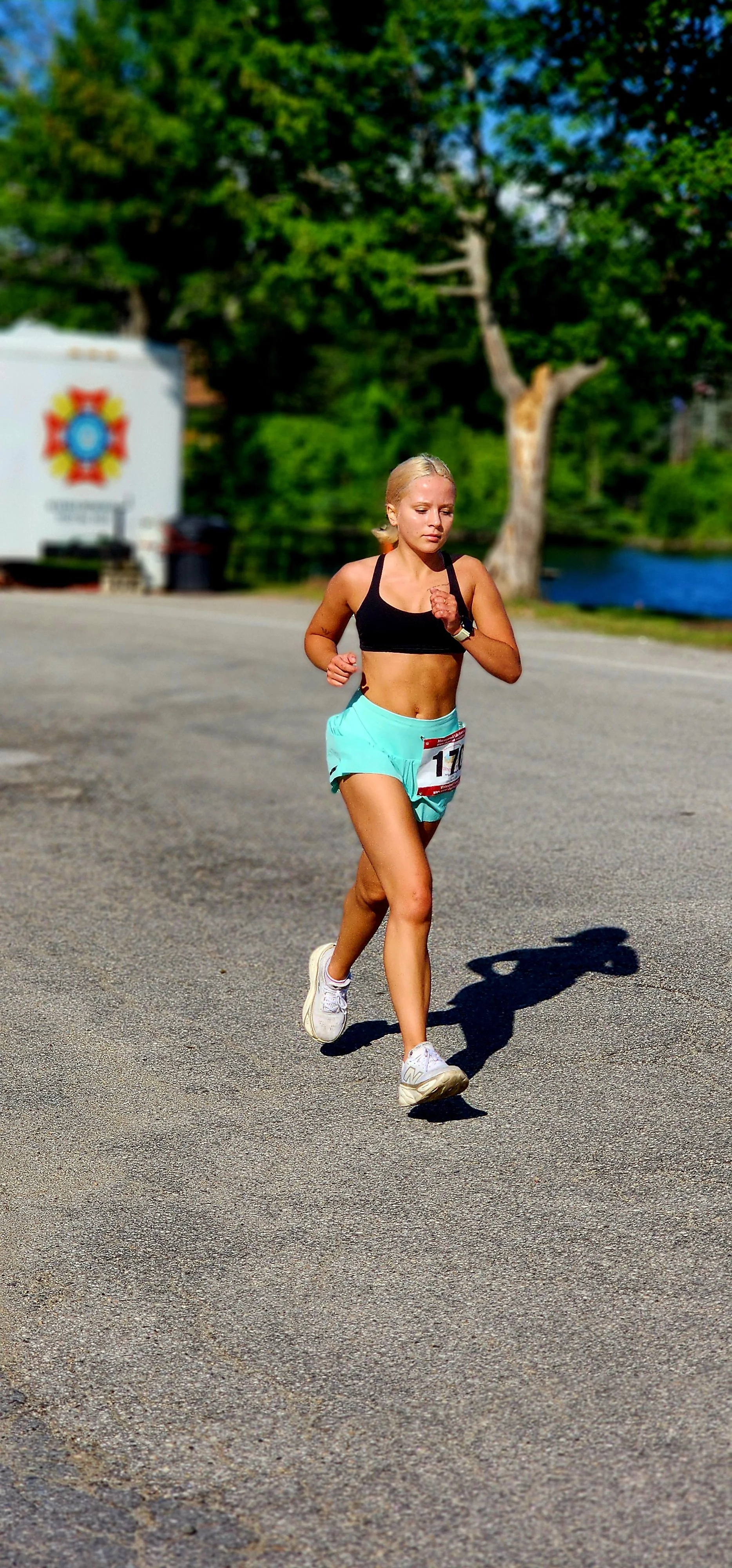 A woman wearing a black sports bra and light blue shorts running