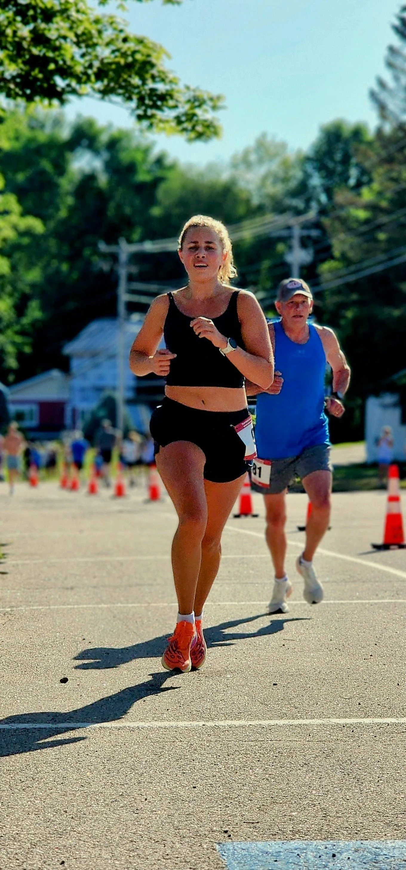 A woman wearing a black tank top and black shorts running
