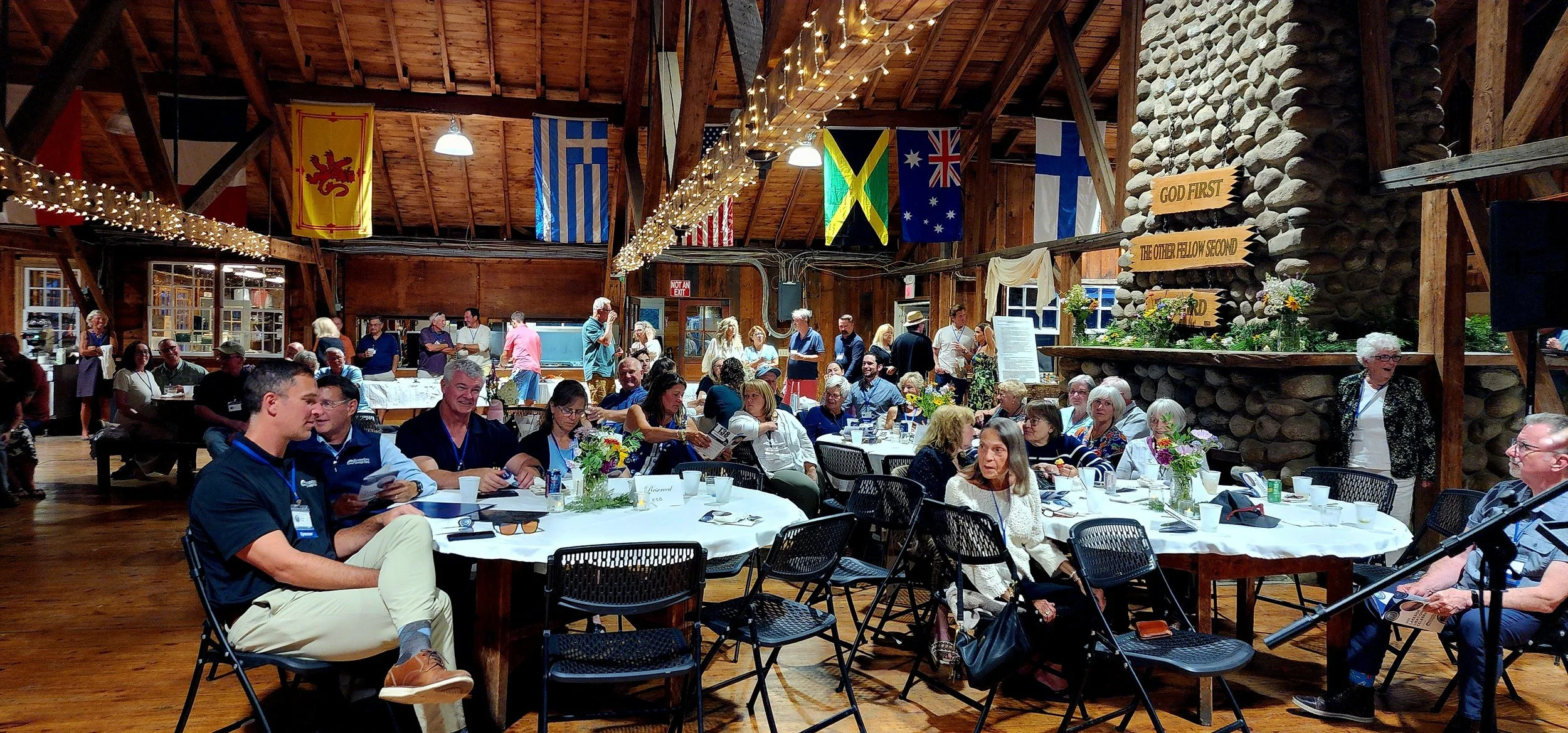 A wide shot of a room with tables and people sitting around them