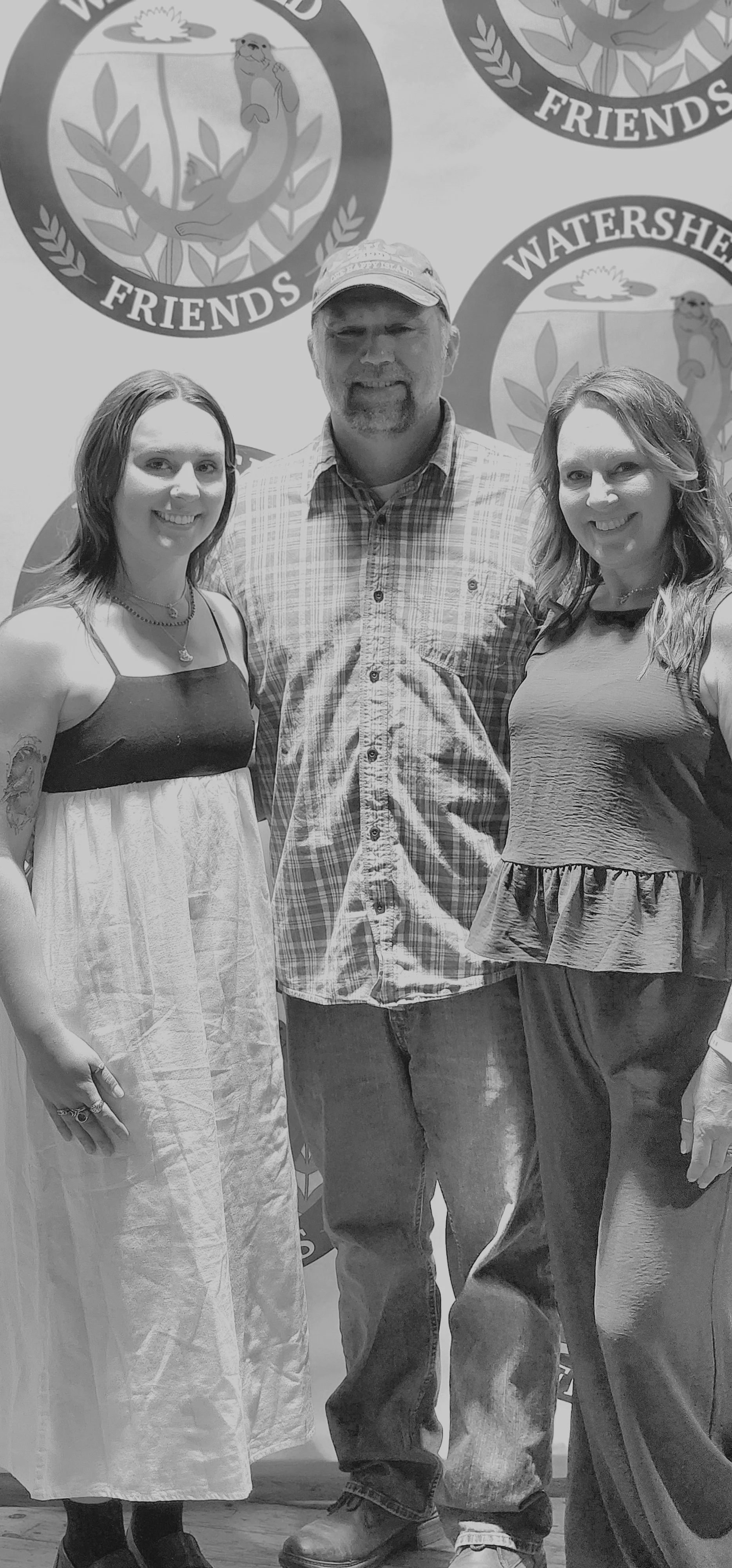 Two women with a man between them smiling at the camera