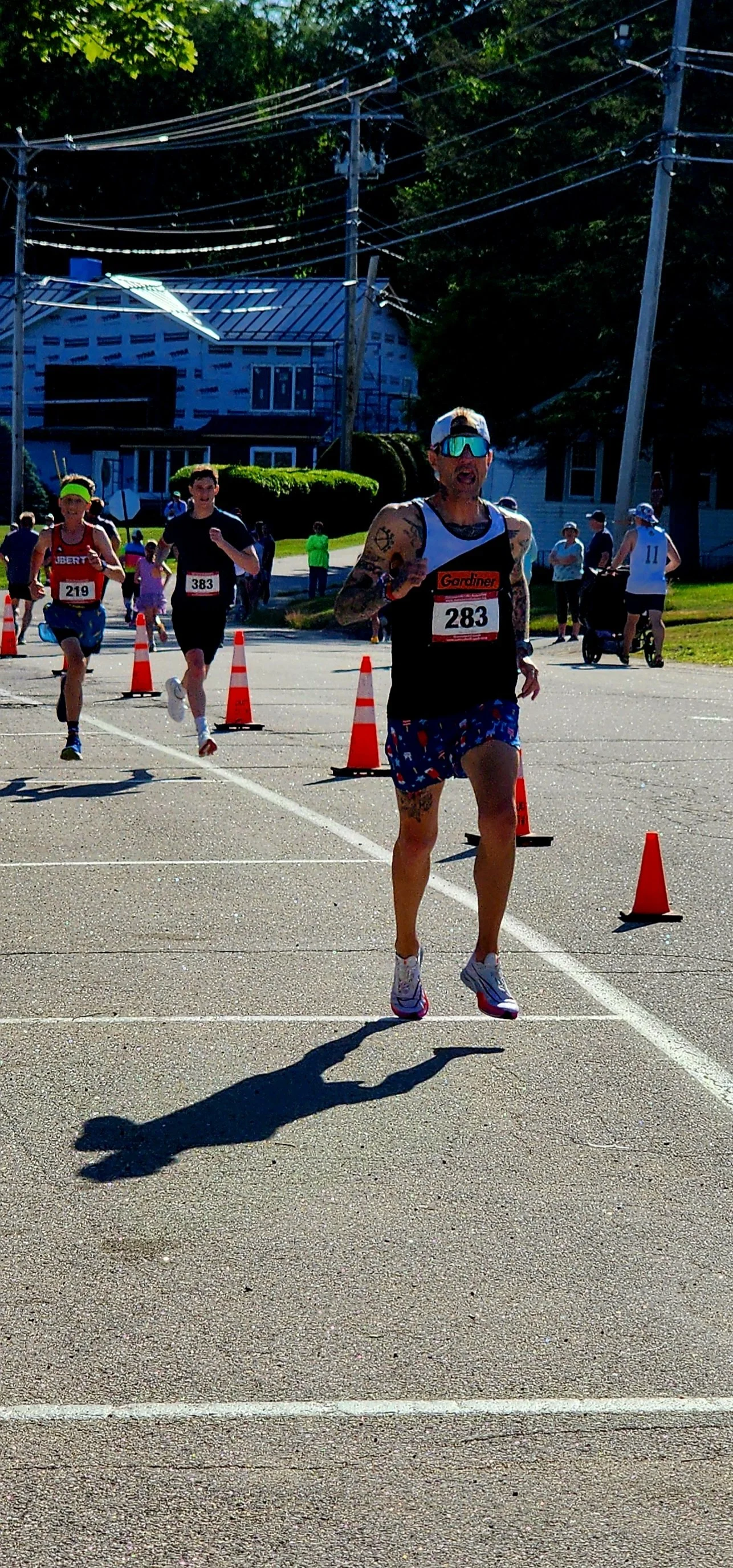 A person wearing a black and white tank top and blue shorts running