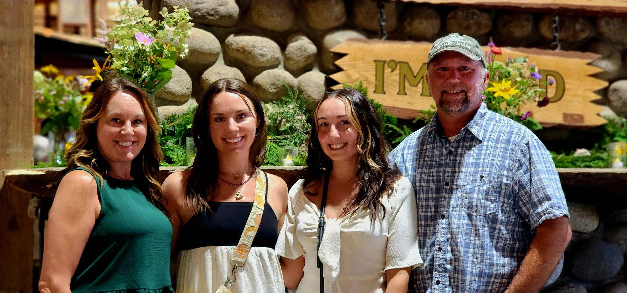Three women and a man smiling at the camera