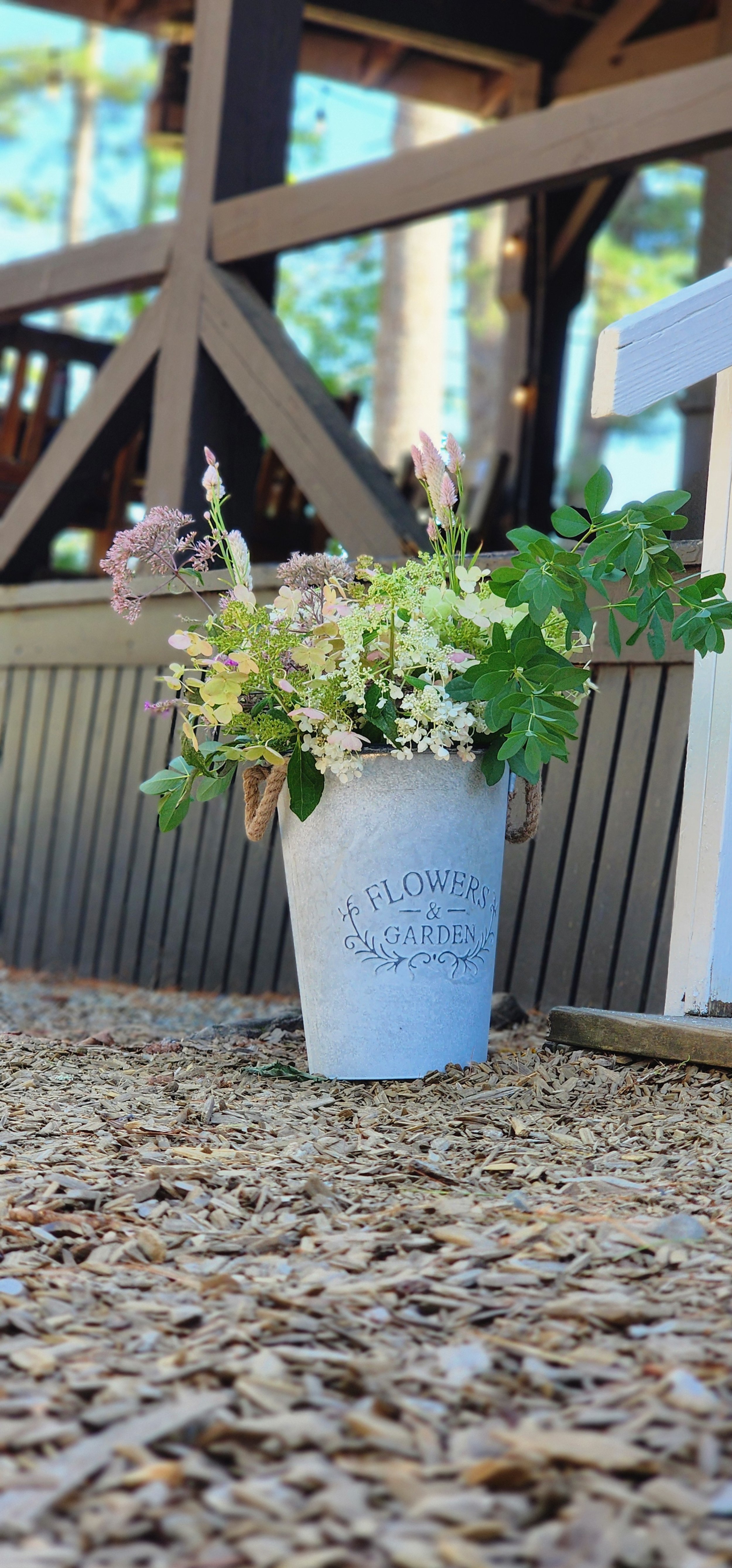 A planter full of flowers sitting into front of a porch