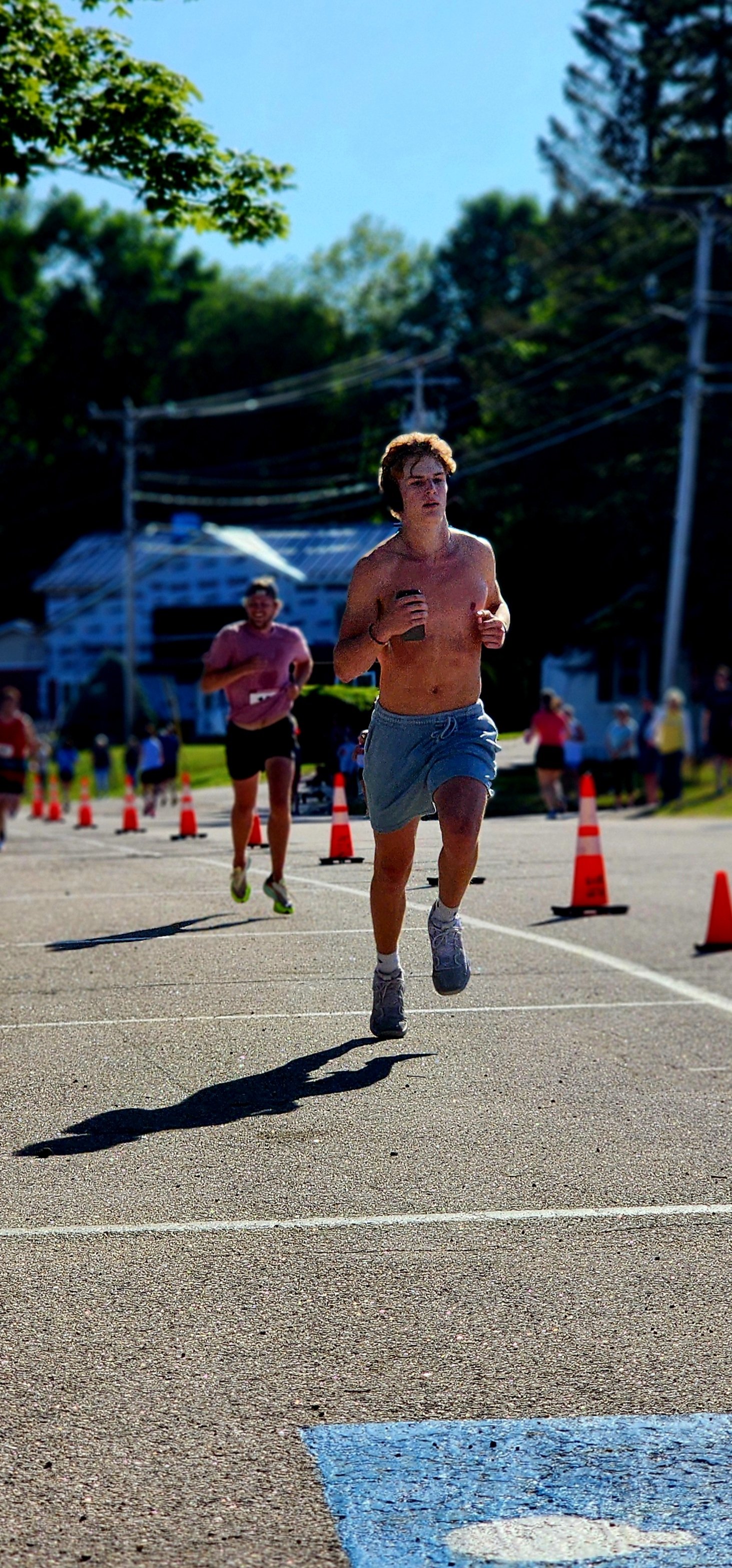 A shirtless man wearing grey shorts running