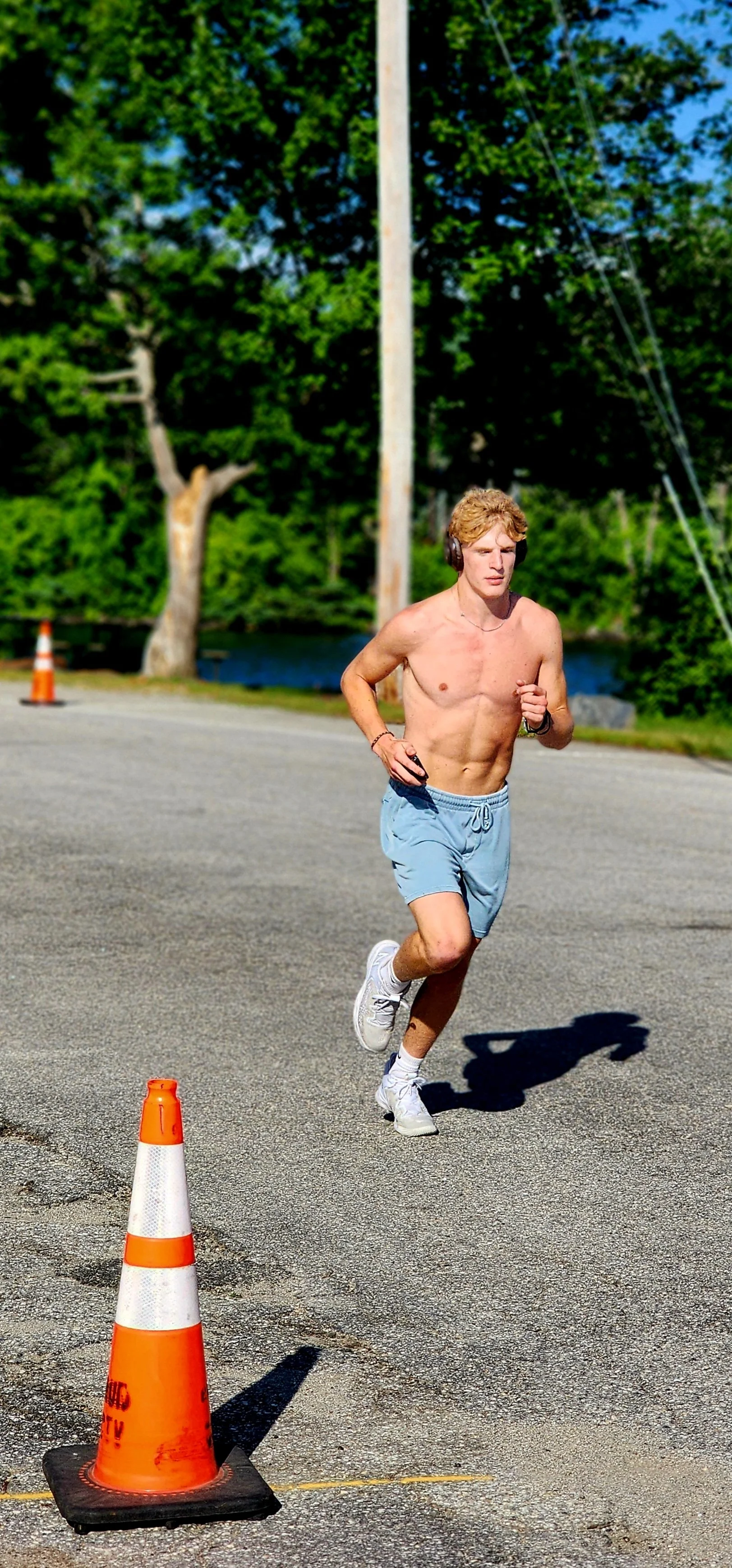 A shirtless man wearing blue shorts running