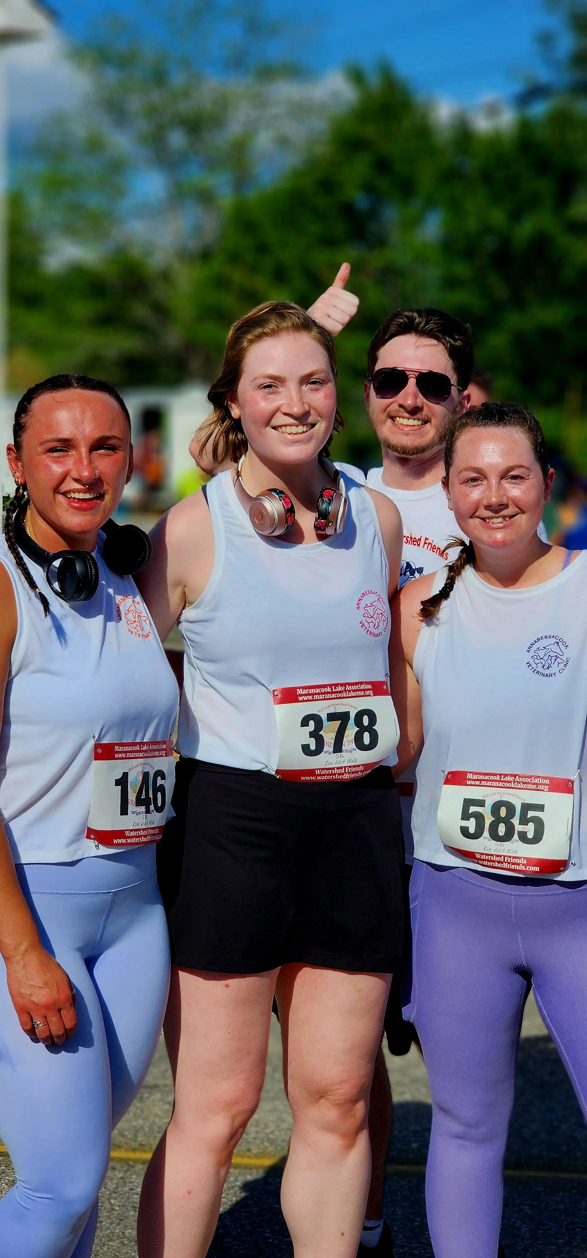 A group of four people wearing white shirts smiling at the camera