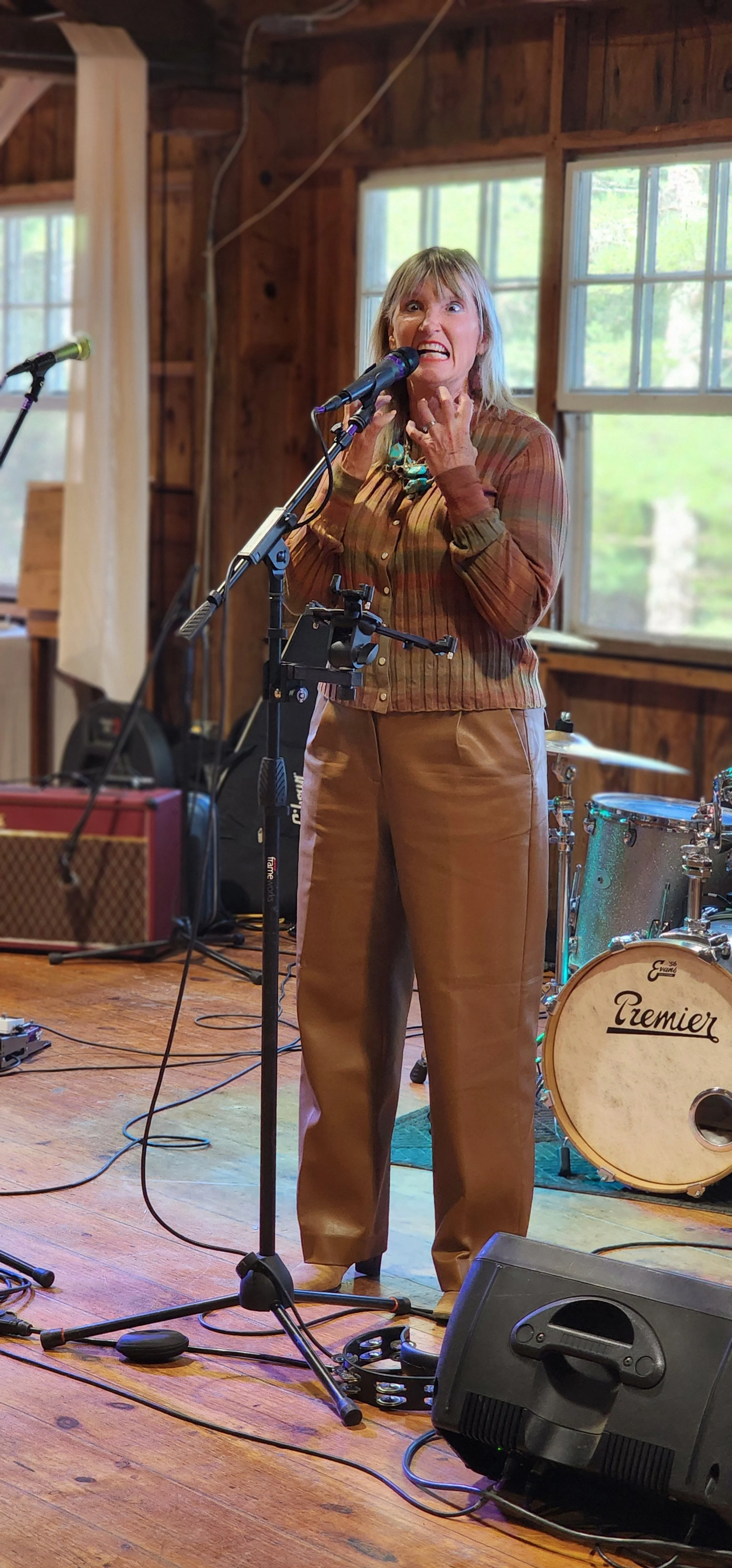 A woman wearing a long sleeve brown shirt and brown pants speaking animatedly into a microphone
