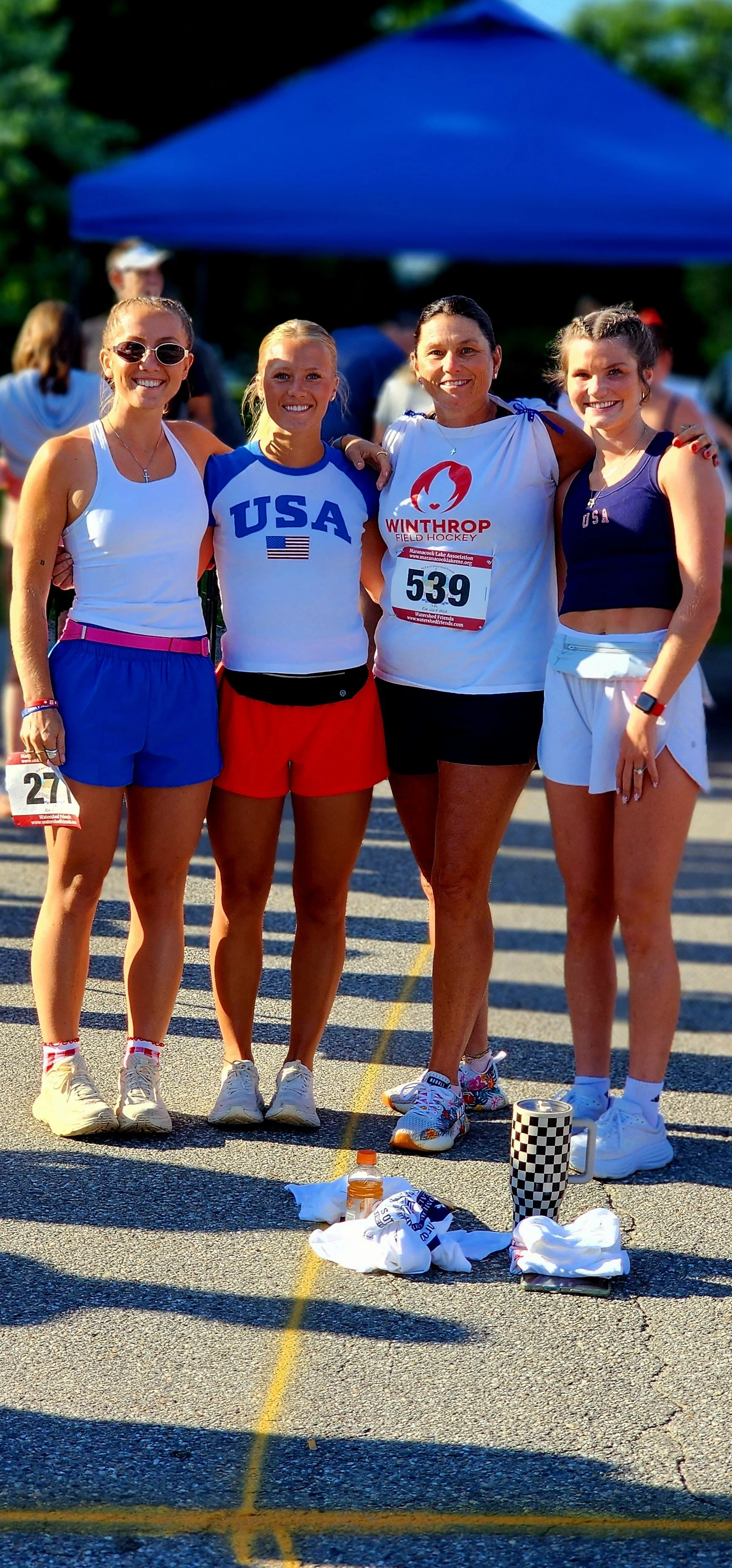 Four women, wearing running clothes, smiling at the camera