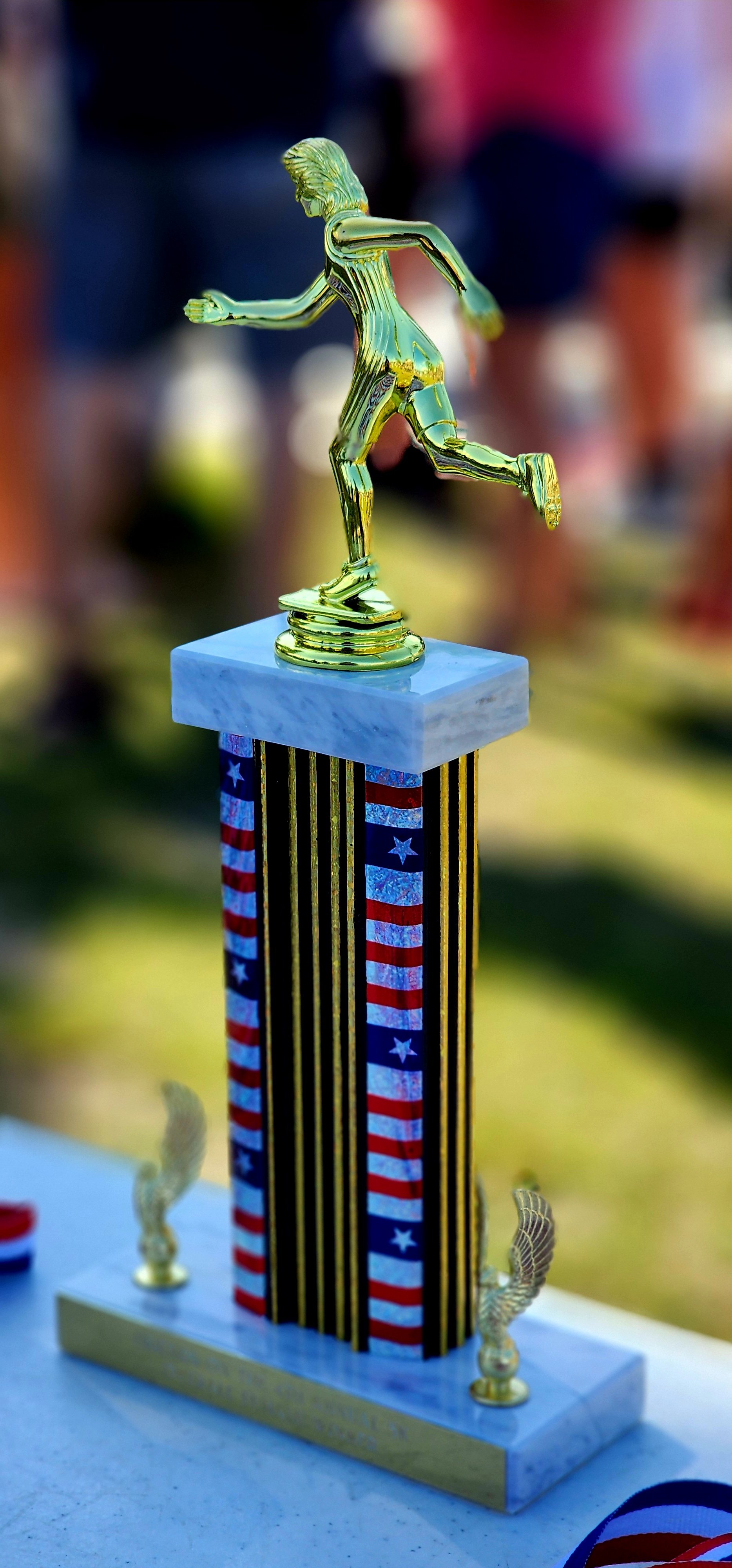 A trophy, with a gold-colored statue of a person running on the top