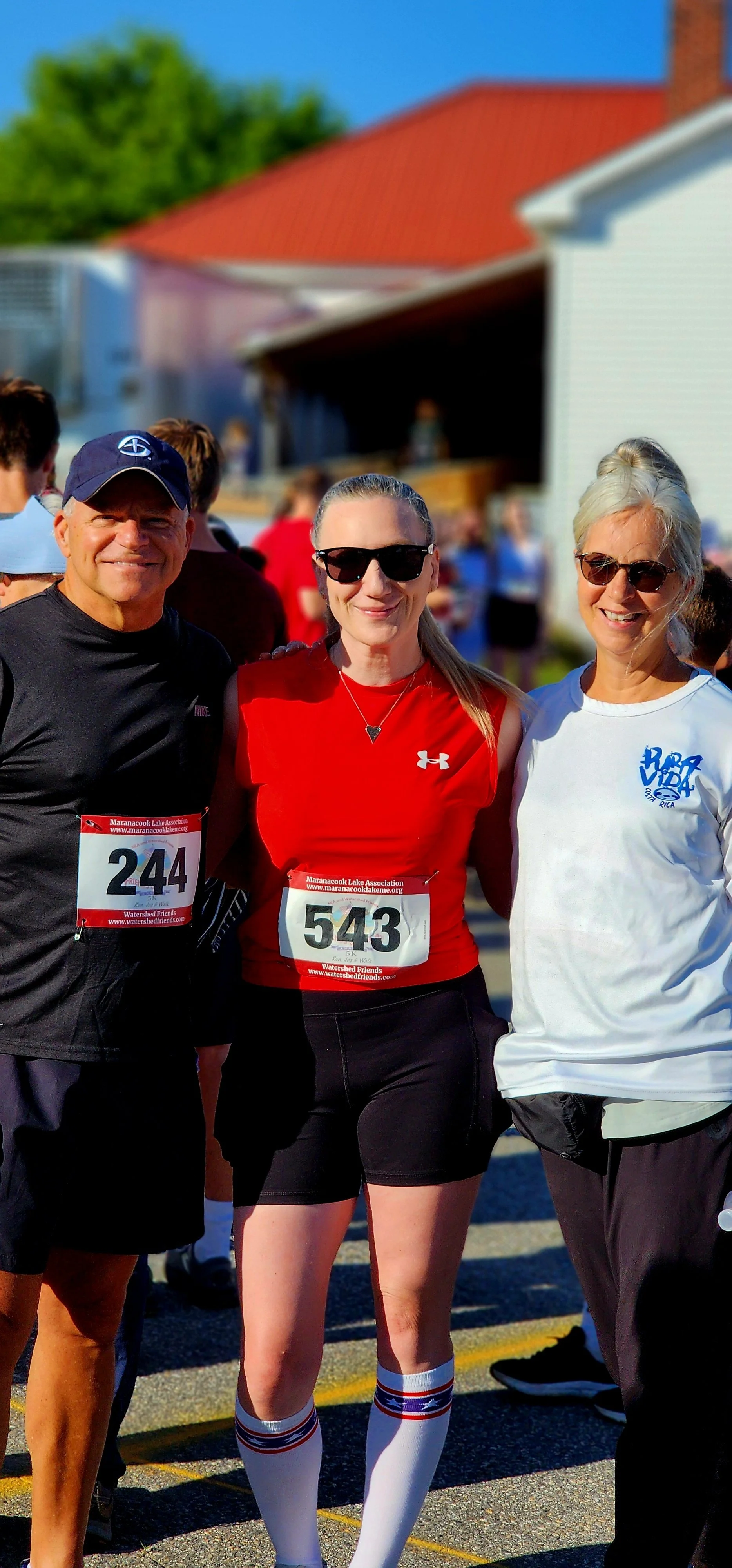 Three people, wearing running clothes, smiling at the camera