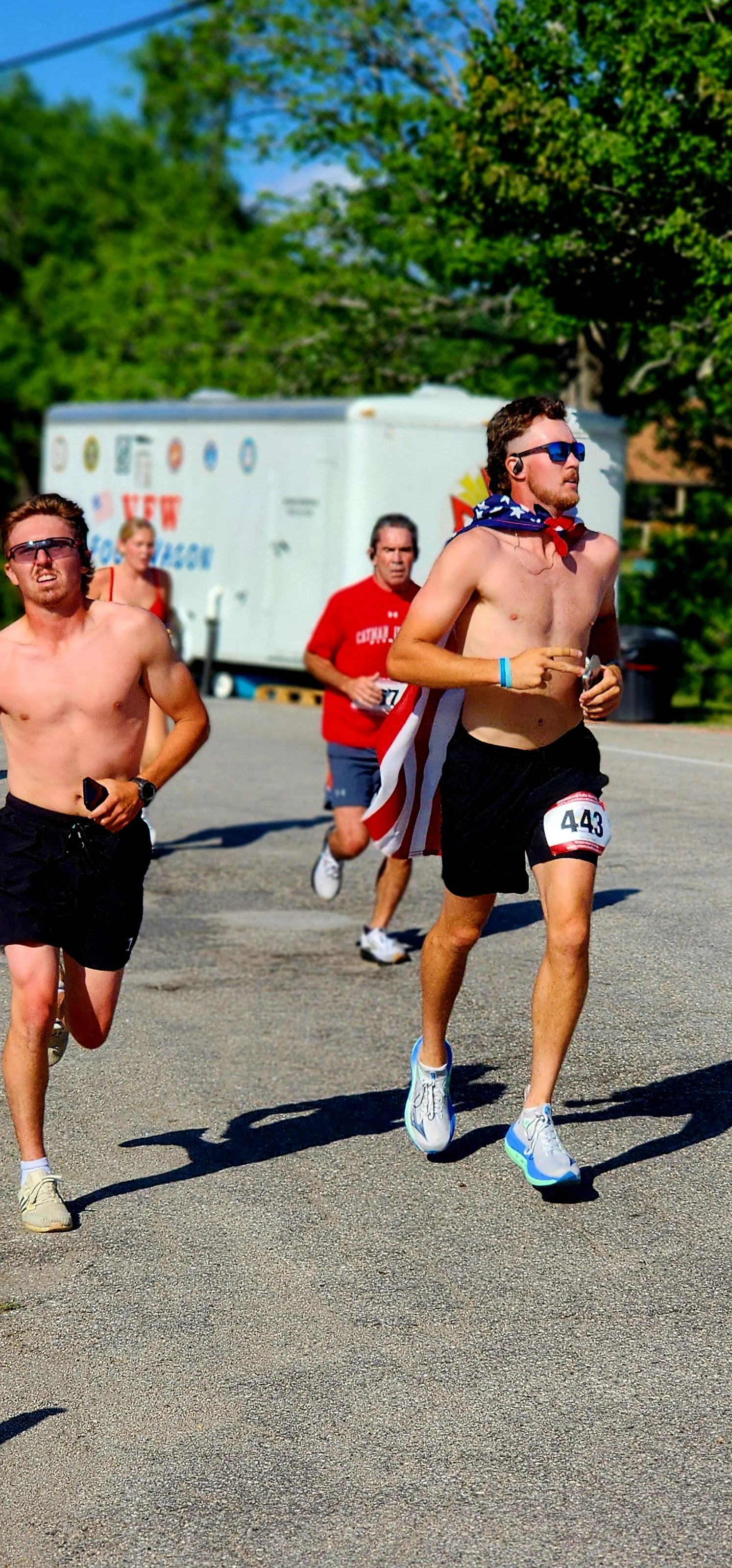 Two shirtless men wearing black shorts running