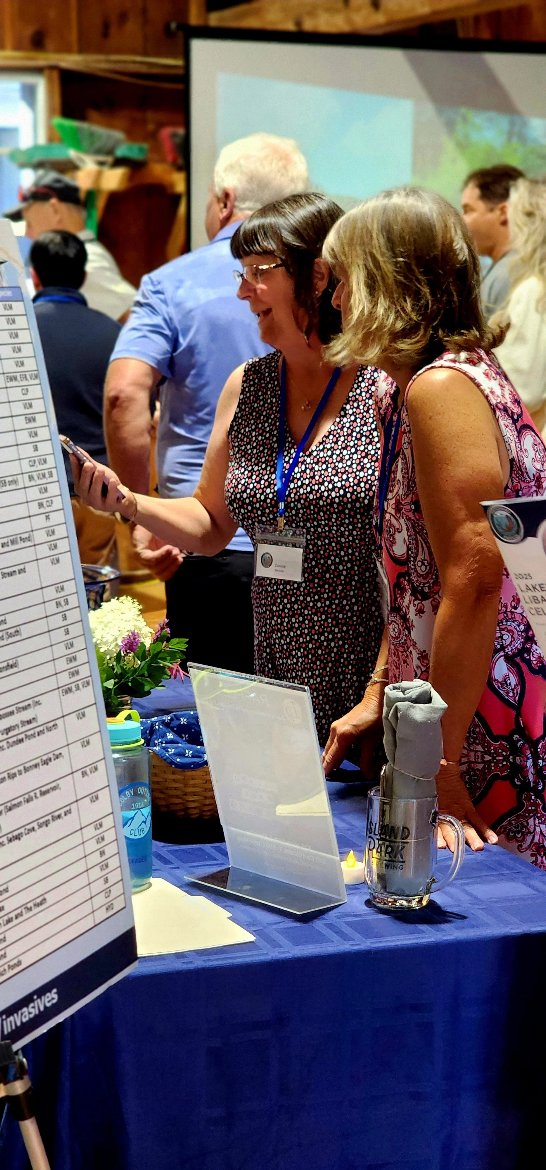 Two women talking to someone off camera in front of a table with signs