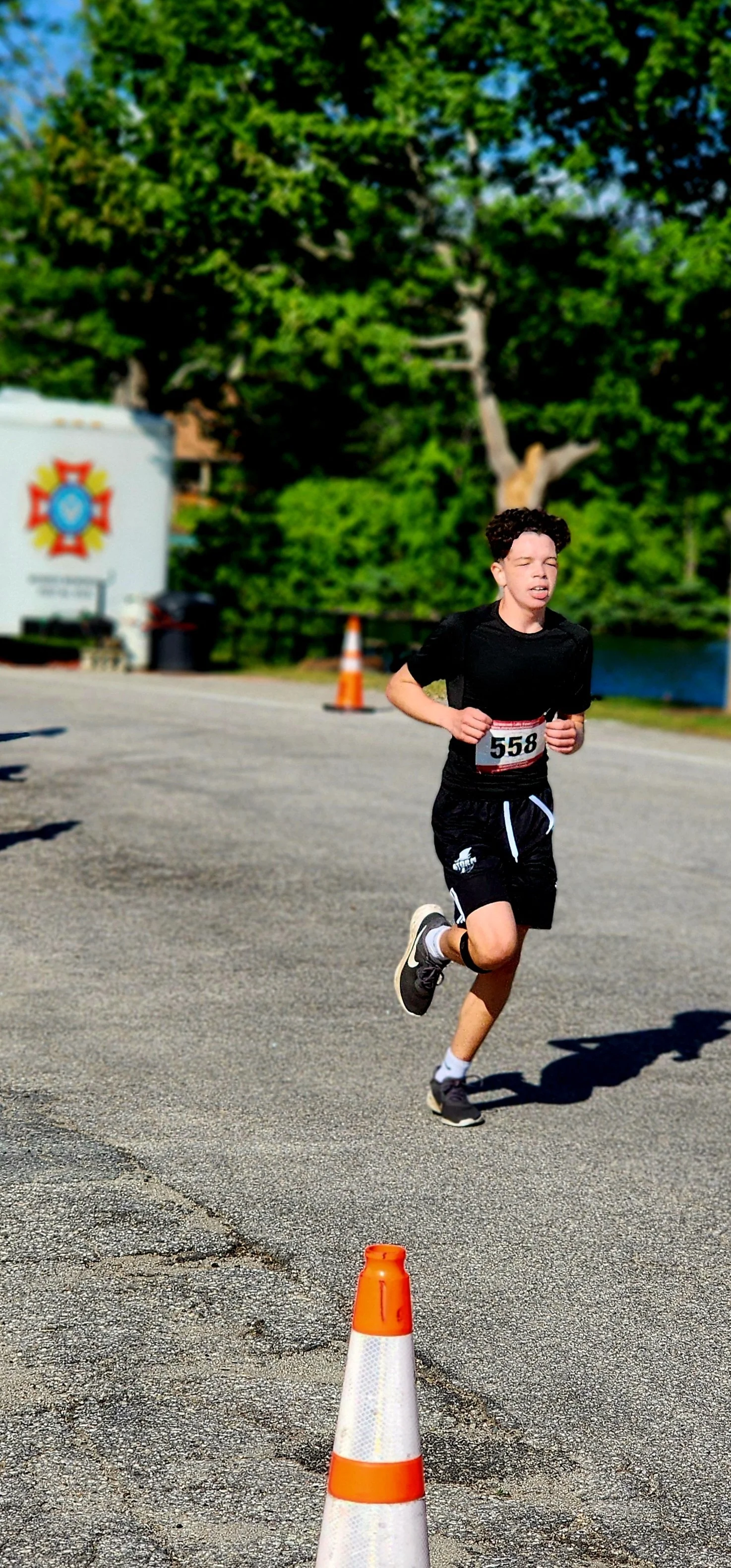 A boy wearing a black t-shirt and shorts running