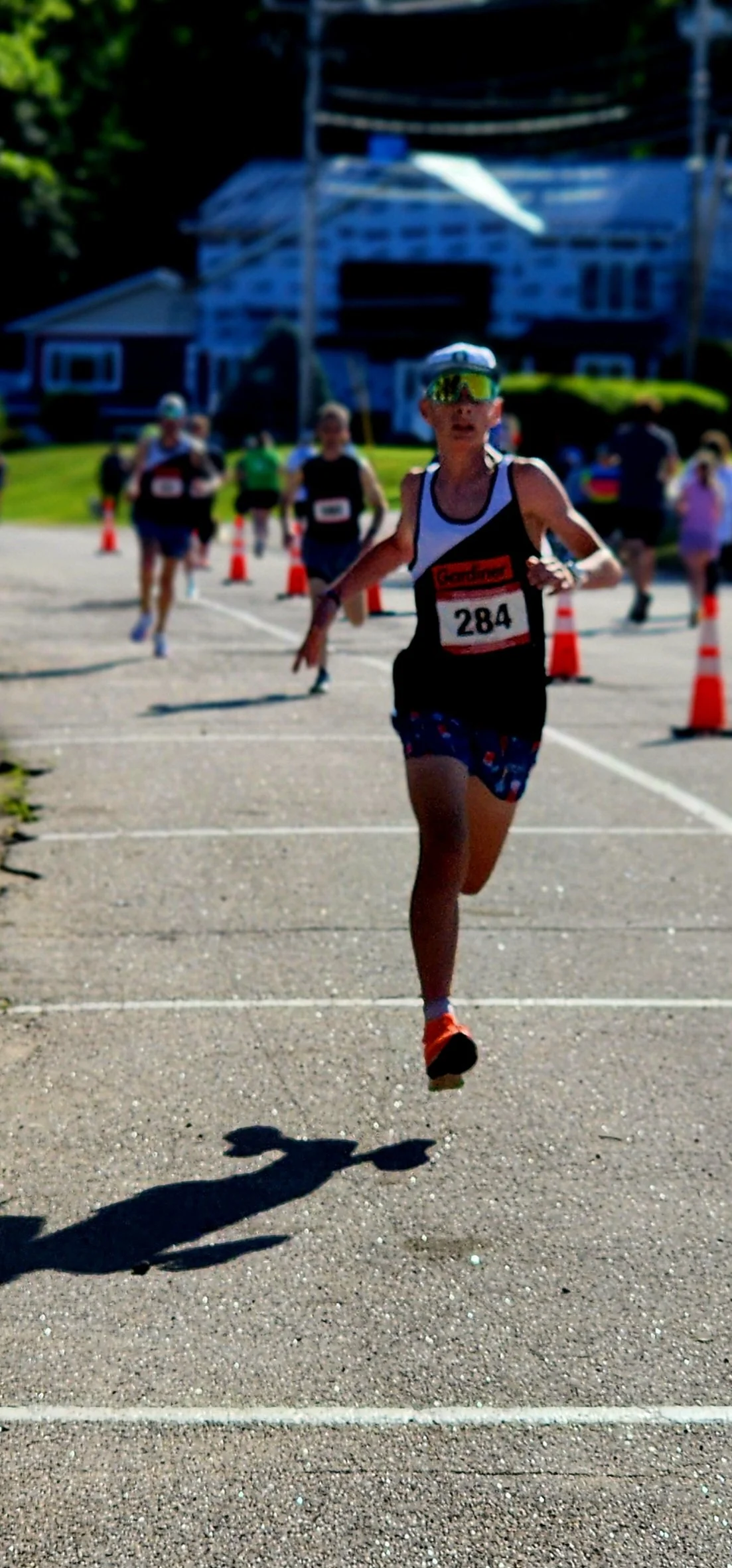 A person wearing a black and white tank top and blue shorts running