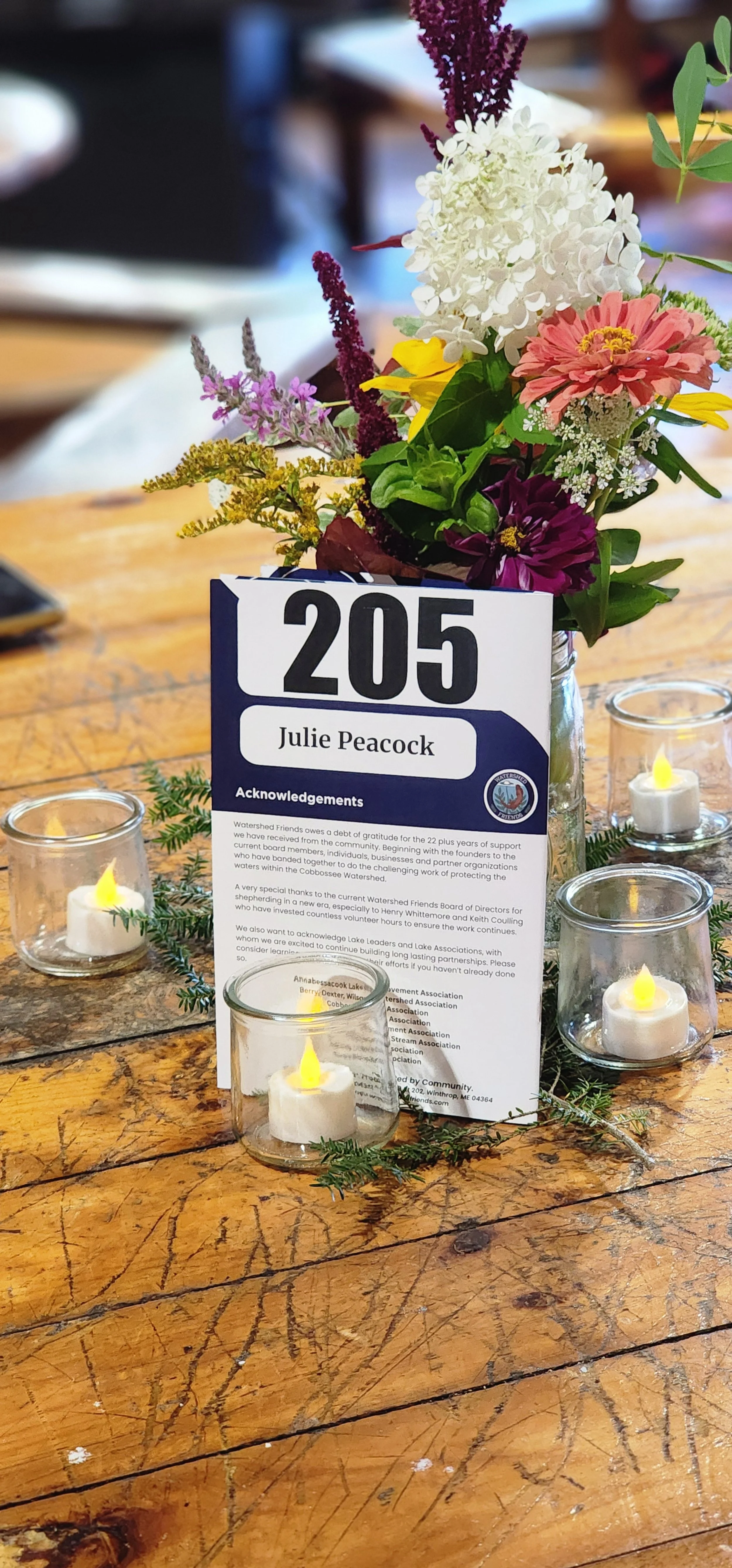A vase of flowers with a event program leaning against it