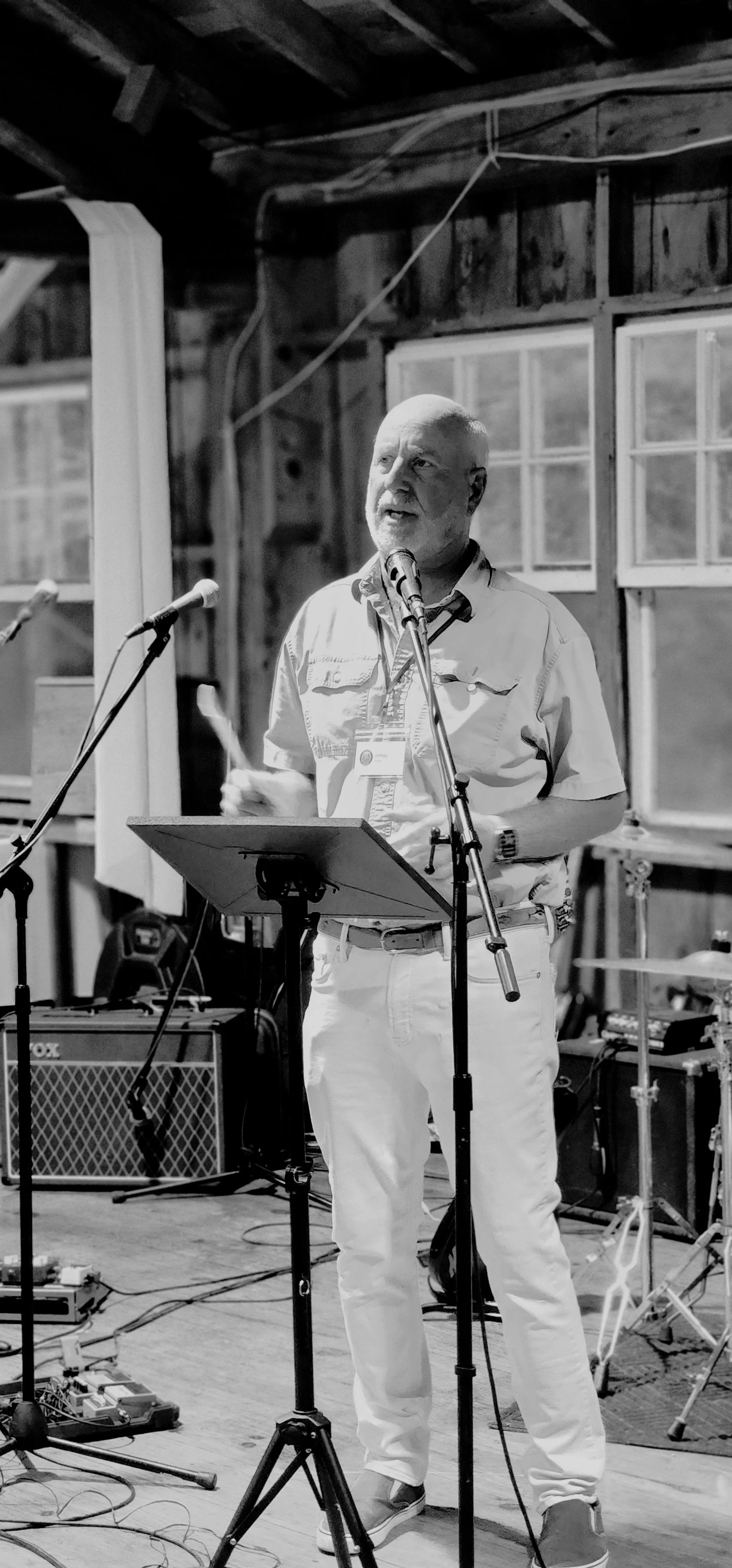 A man, wearing a short sleeve button up shirt, speaking into a microphone