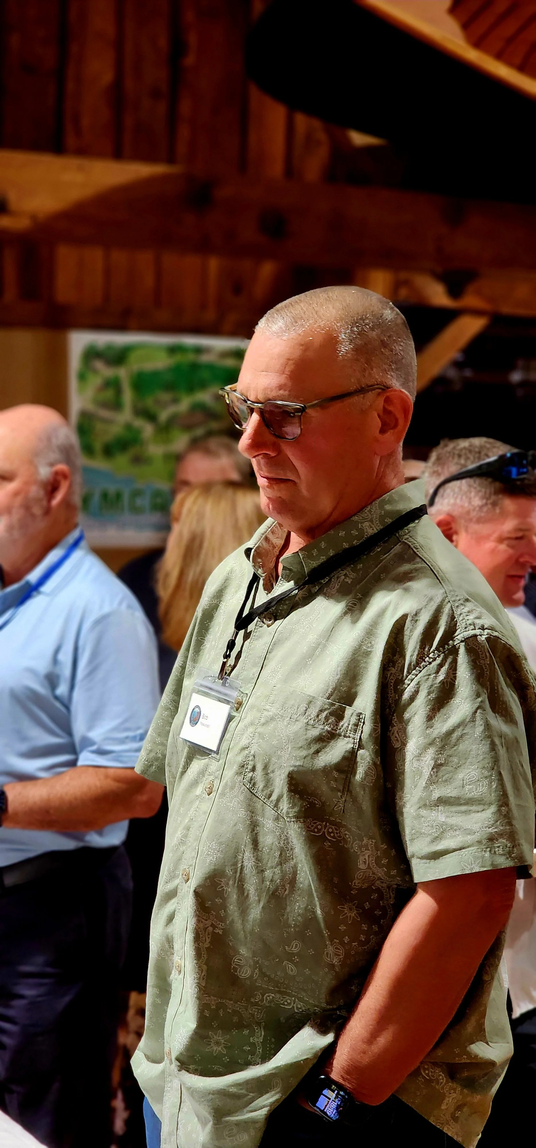 A man, wearing a green short sleeve button up, watching something off camera