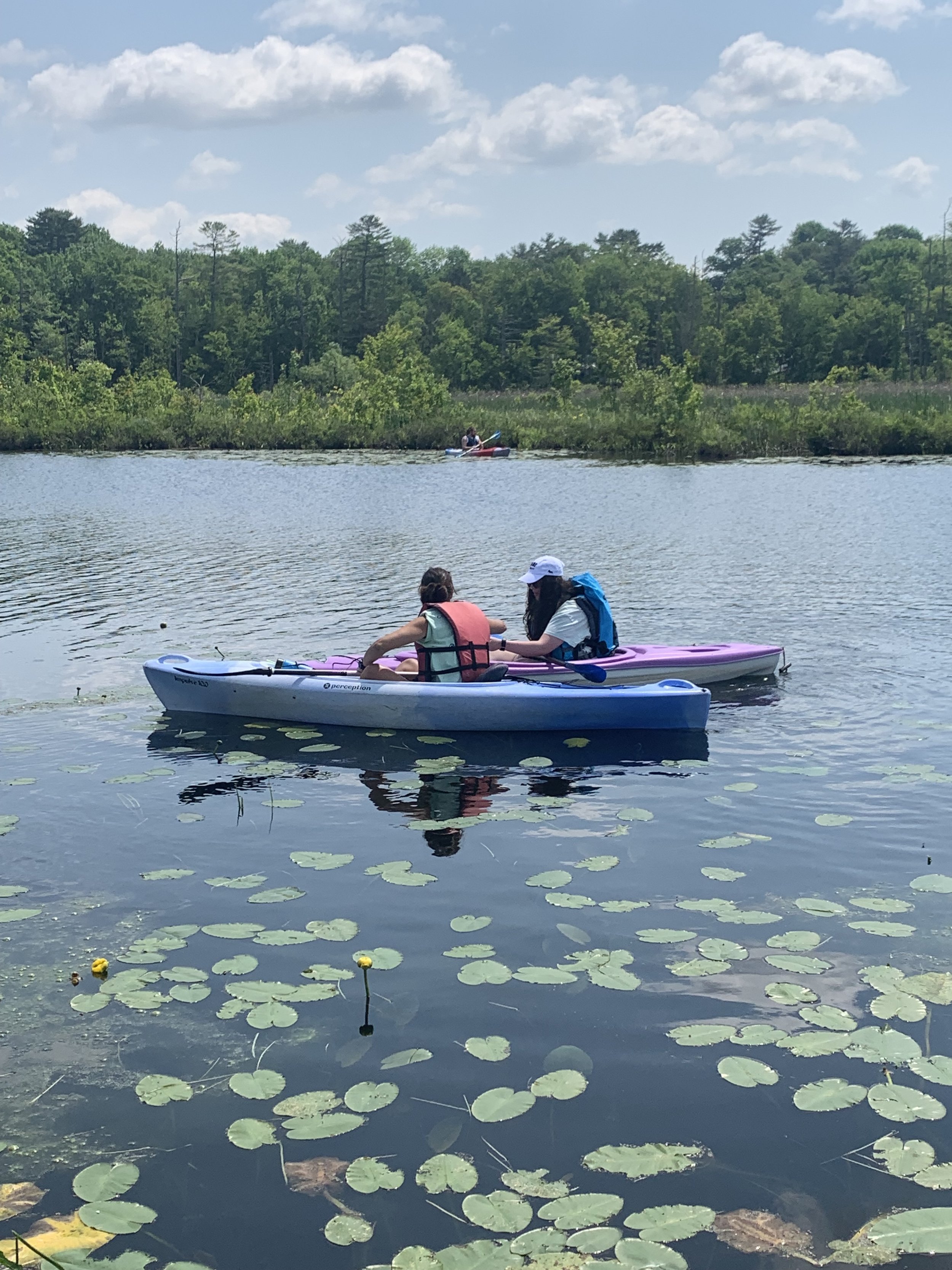 Two kayakers side by side, both looking at something held in one of their hands