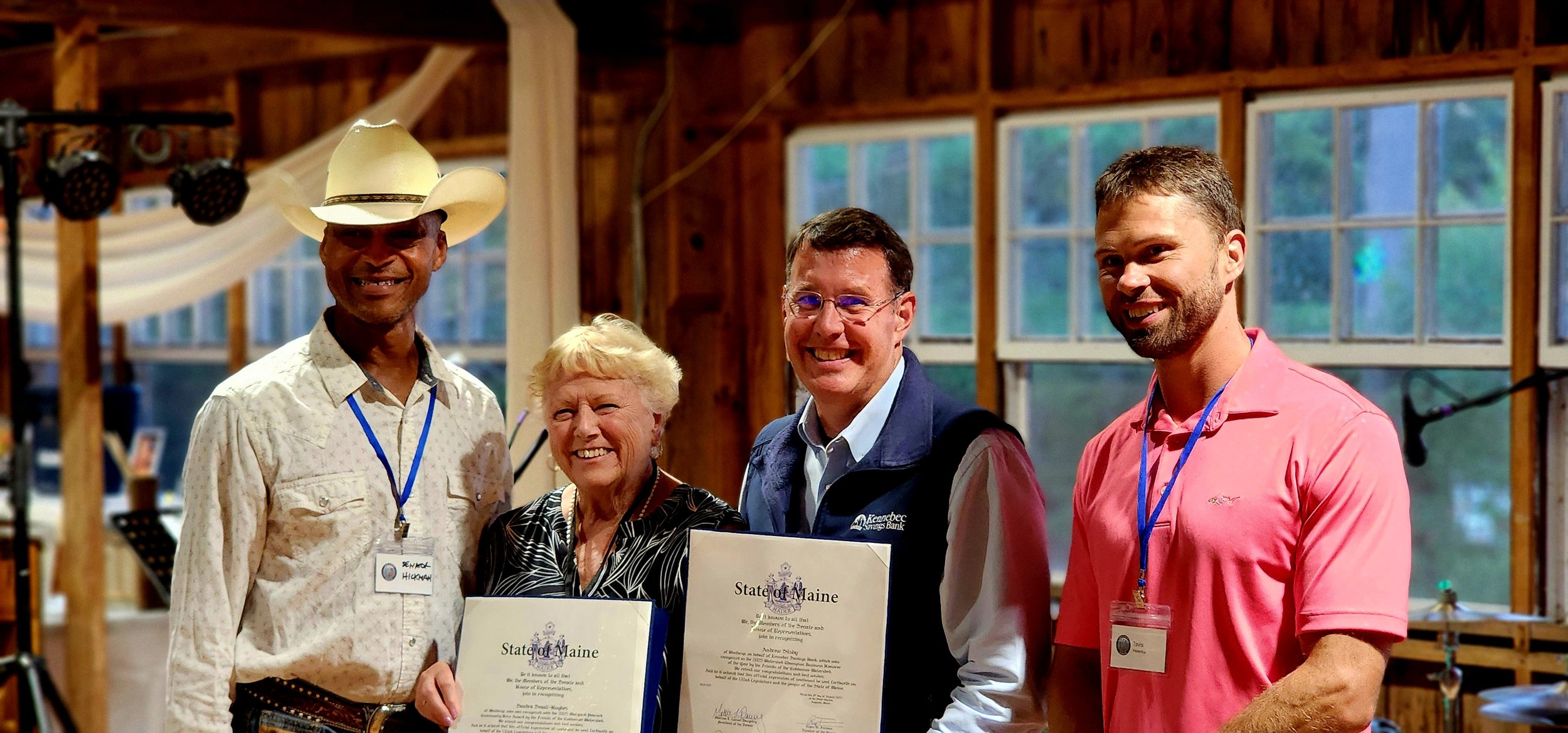 A man on the left, a woman, and two other men, the woman and man to the left of her holding certificates