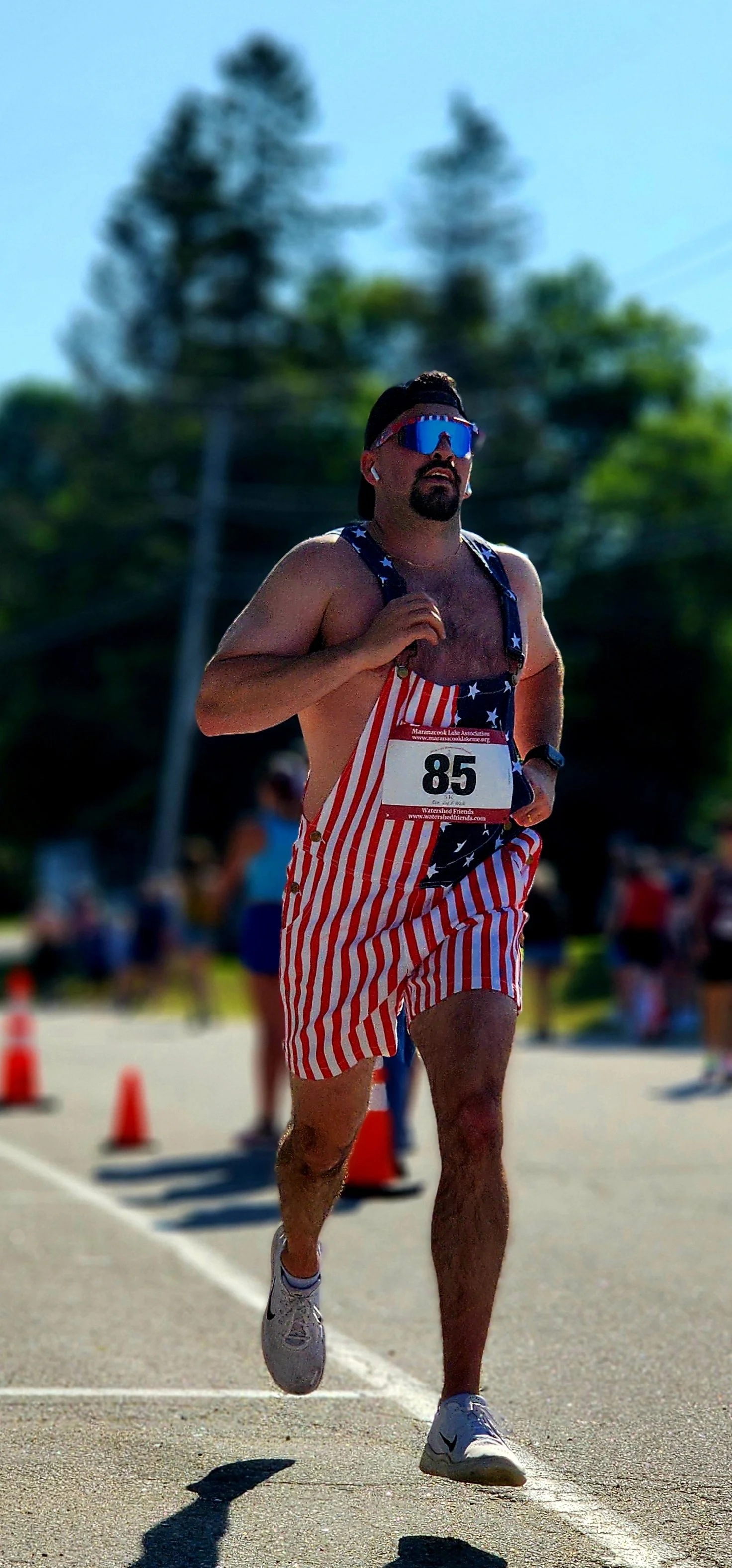 A man wearing a pair of American flag patterned overall shorts running