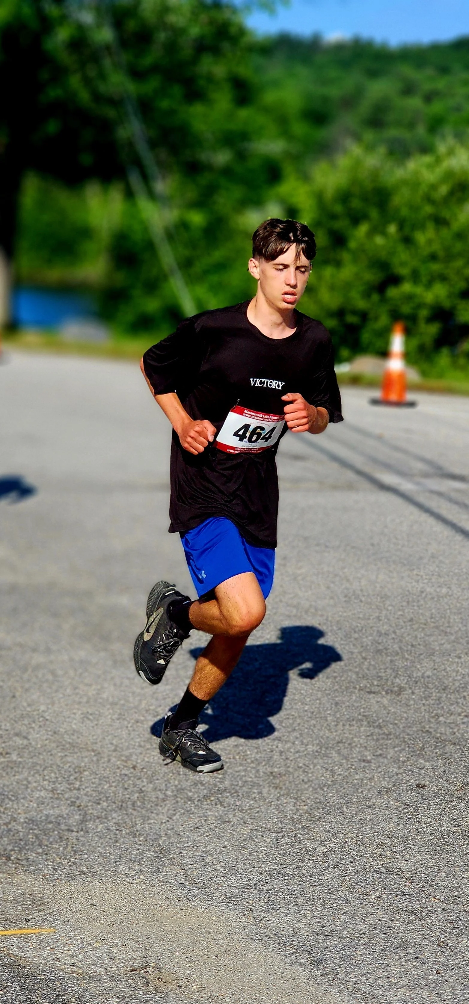 A boy wearing a black t-shirt and blue shorts running