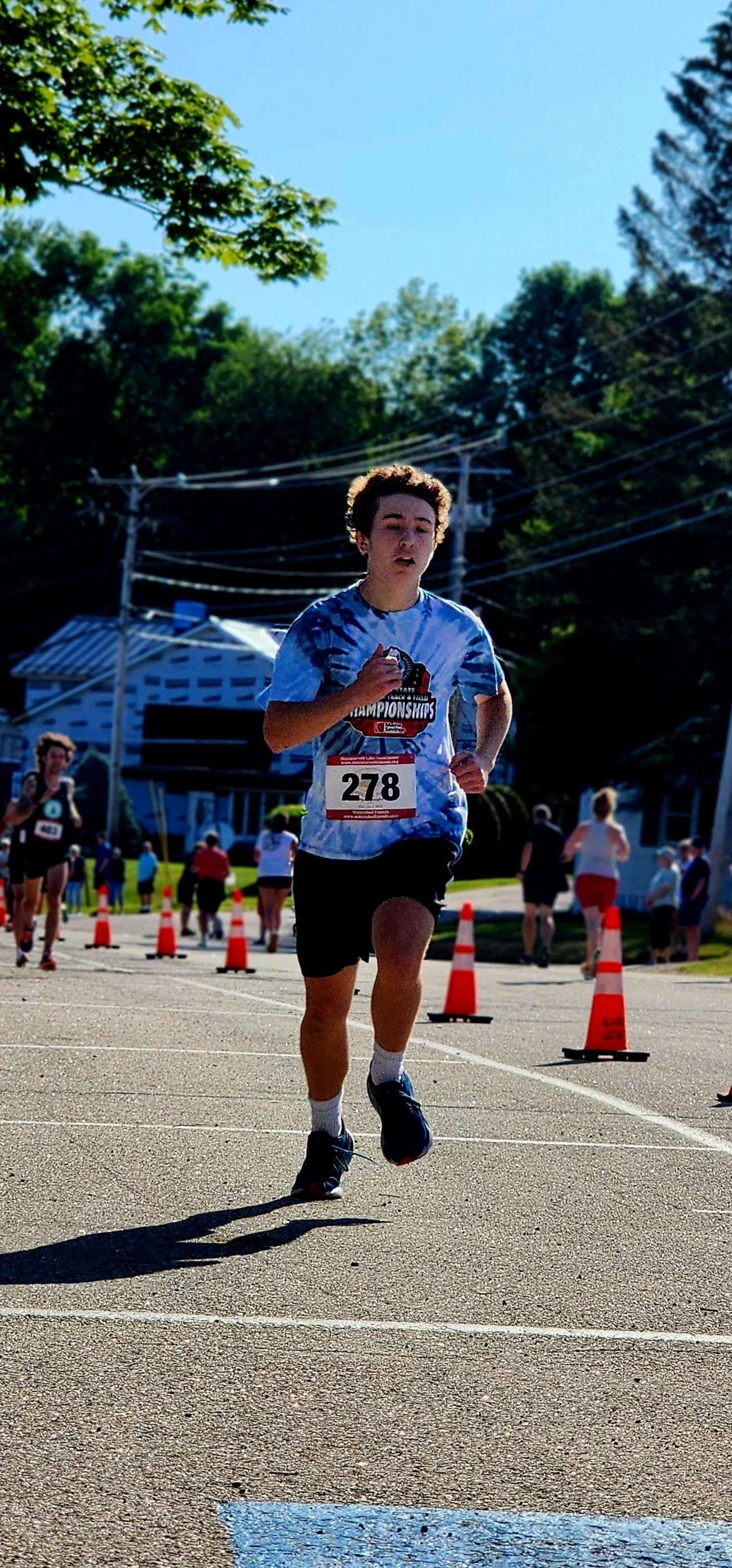 A man wearing a tie-dyed shirt and black shorts running