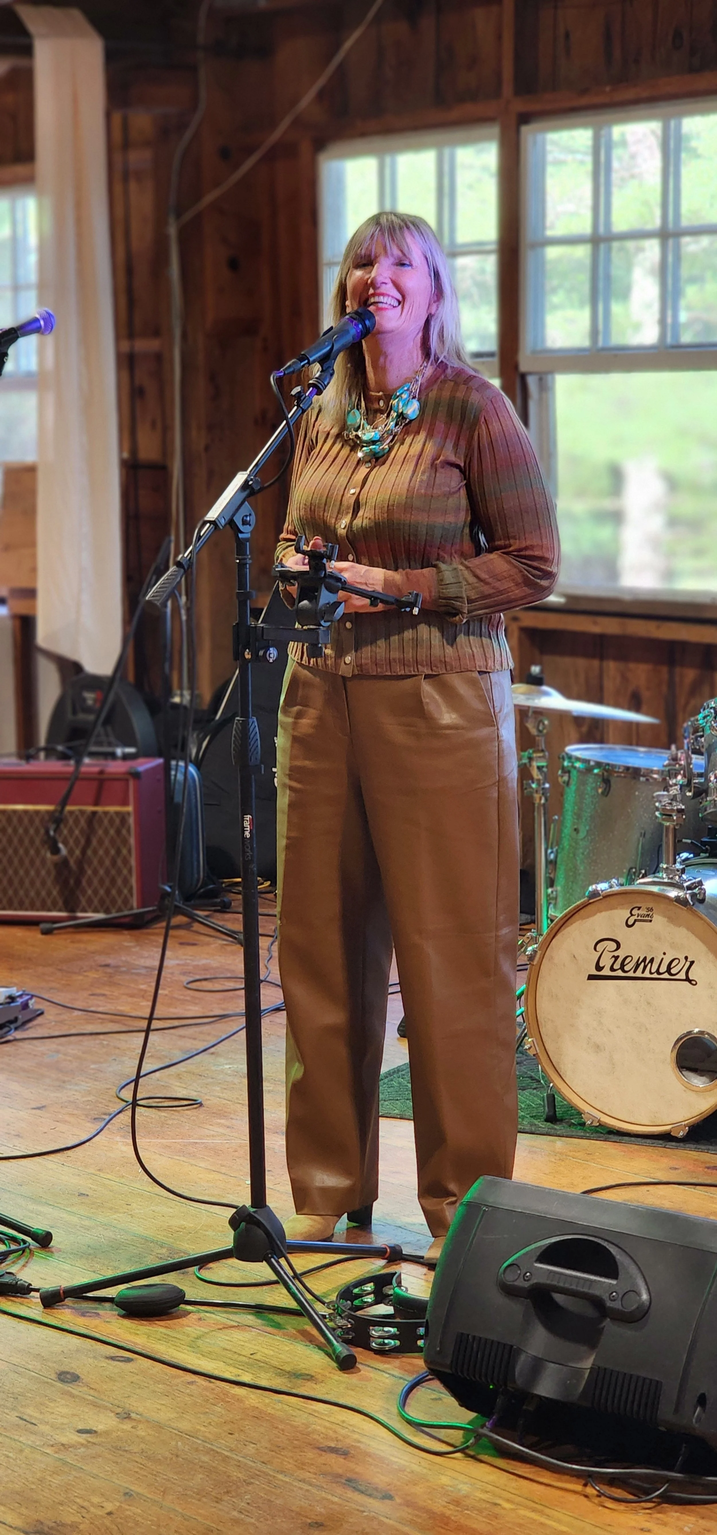 A woman wearing a long sleeve brown shirt and brown pants speaking into a microphone