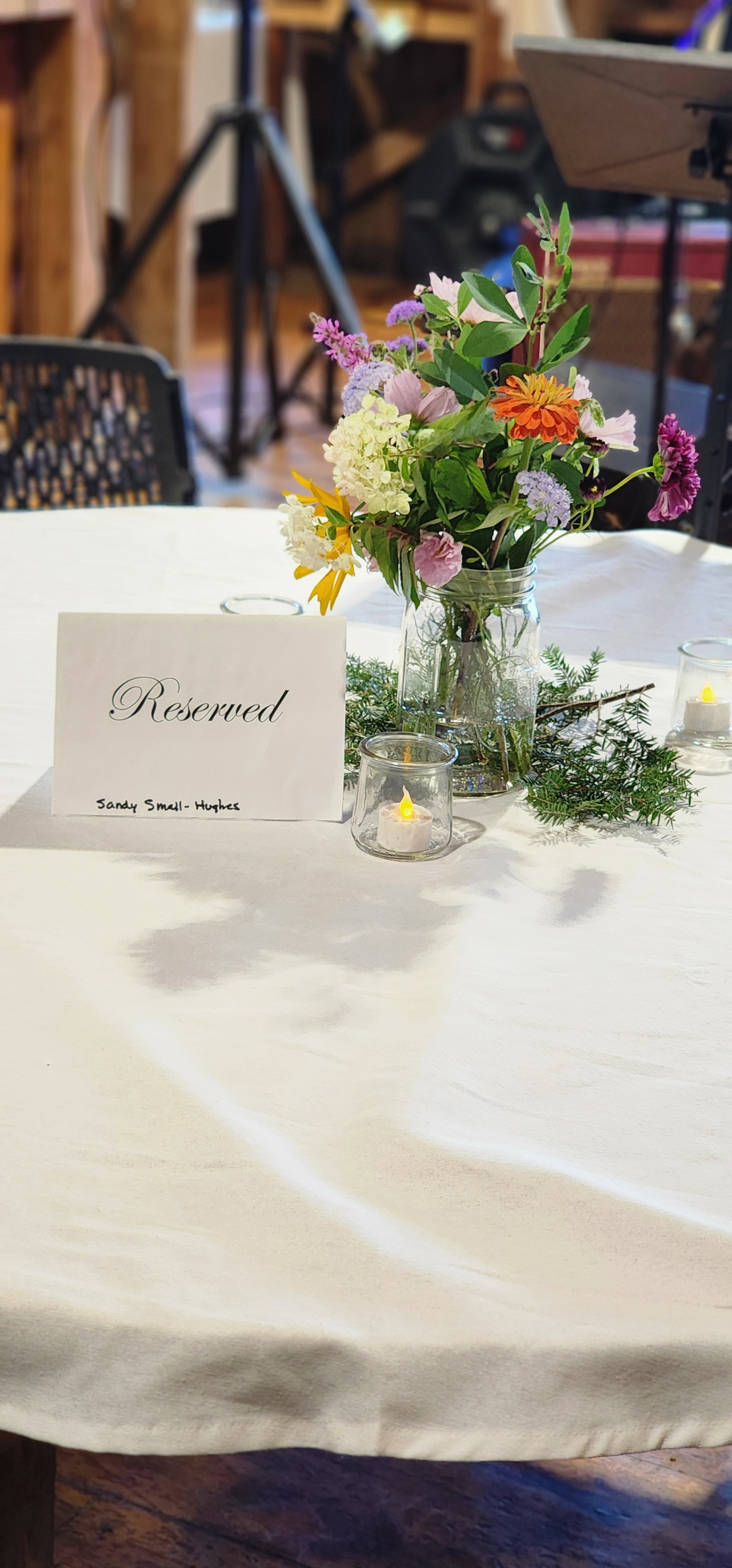 A vase with flowers and a sign saying "Reserved" on a white tablecloth