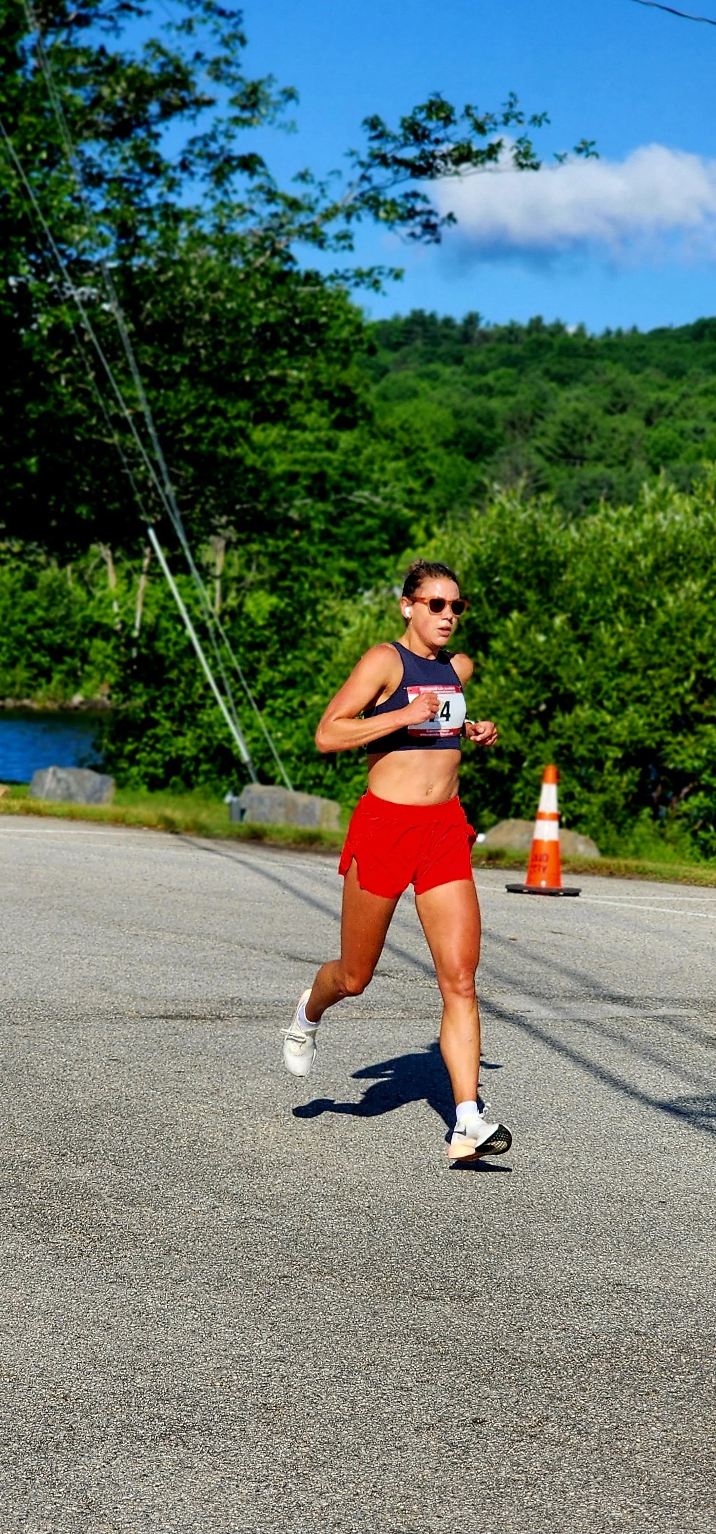 A woman wearing a blue sports bra and red shorts running