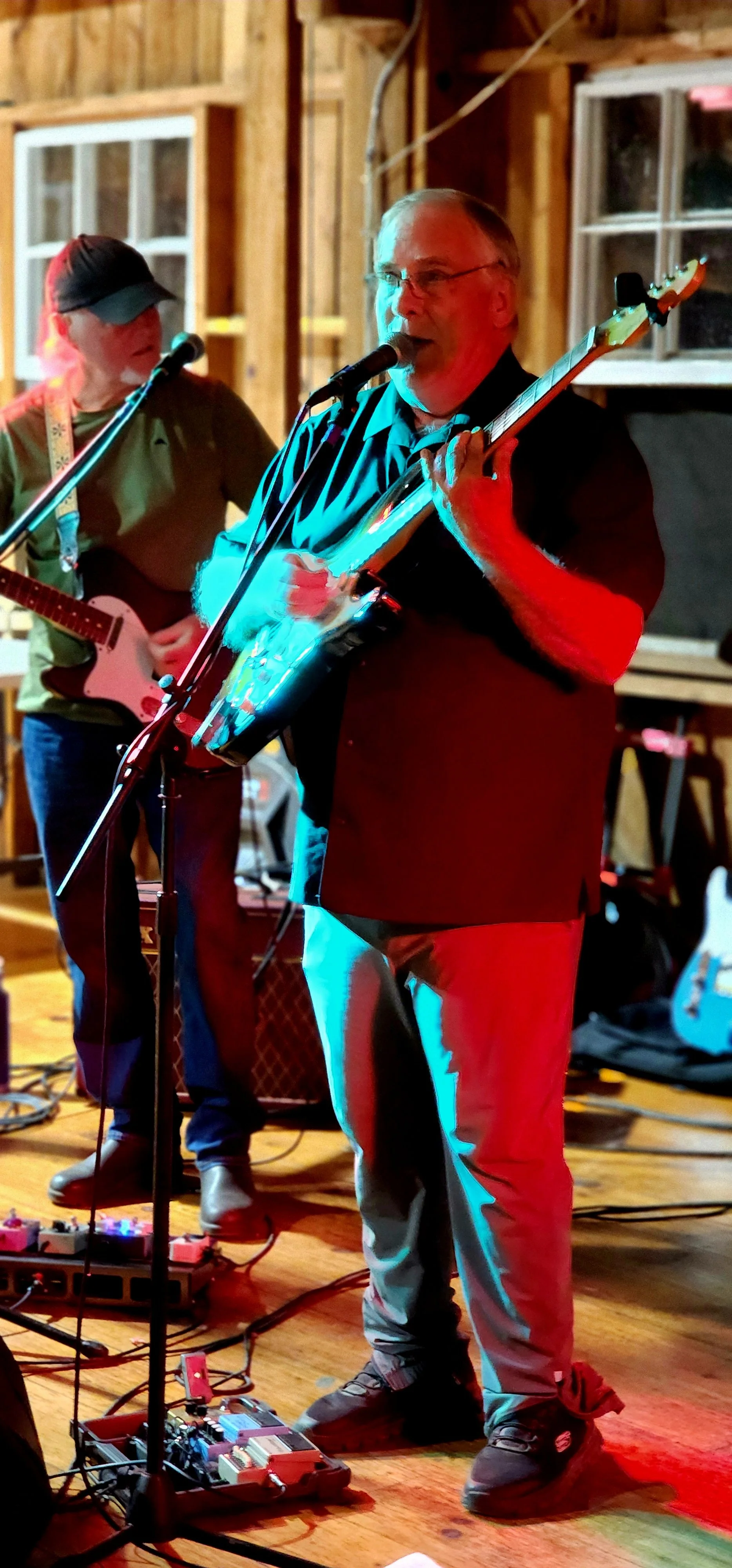 A man singing into a microphone and playing guitar