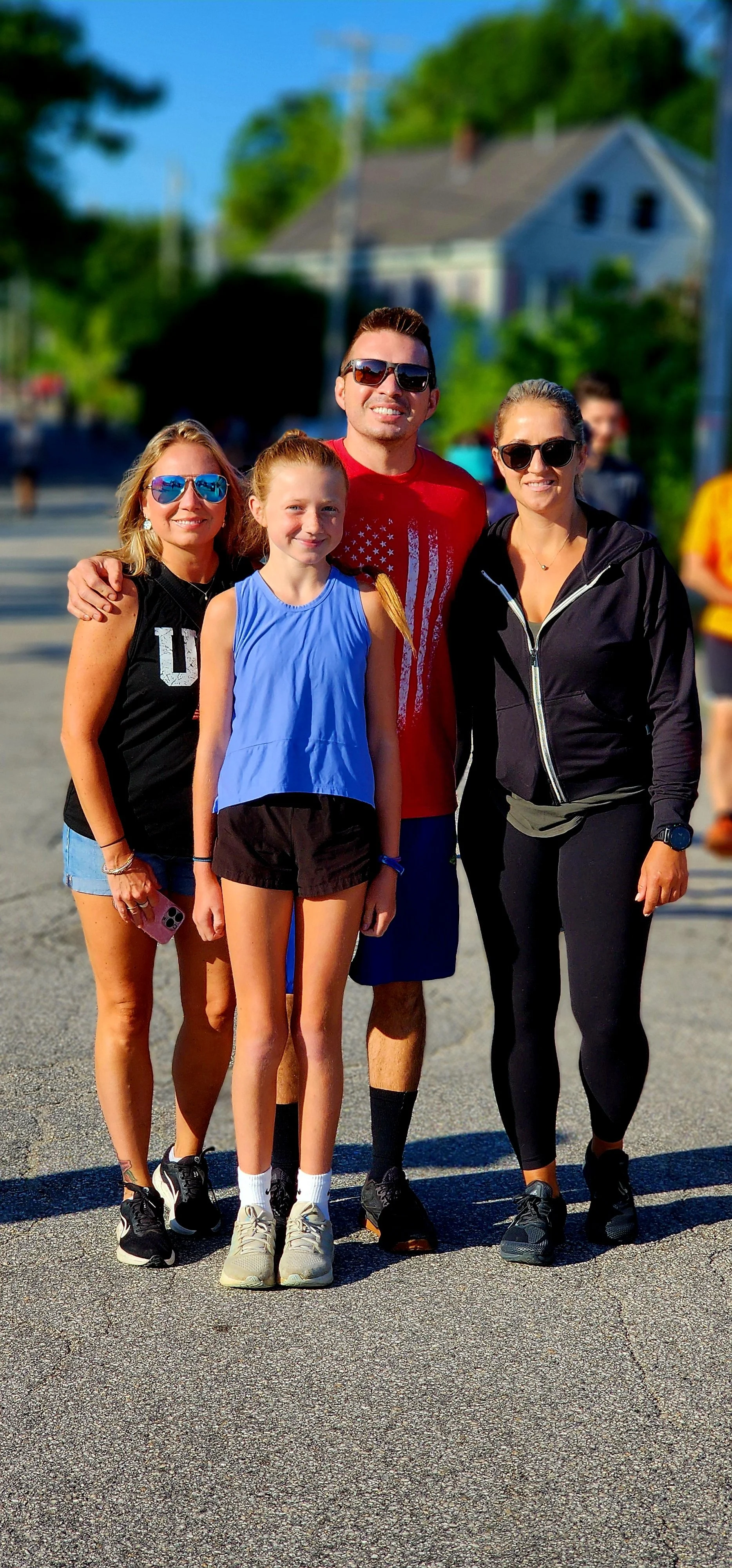 A group of four people dressed in running clothes smiling at the camera