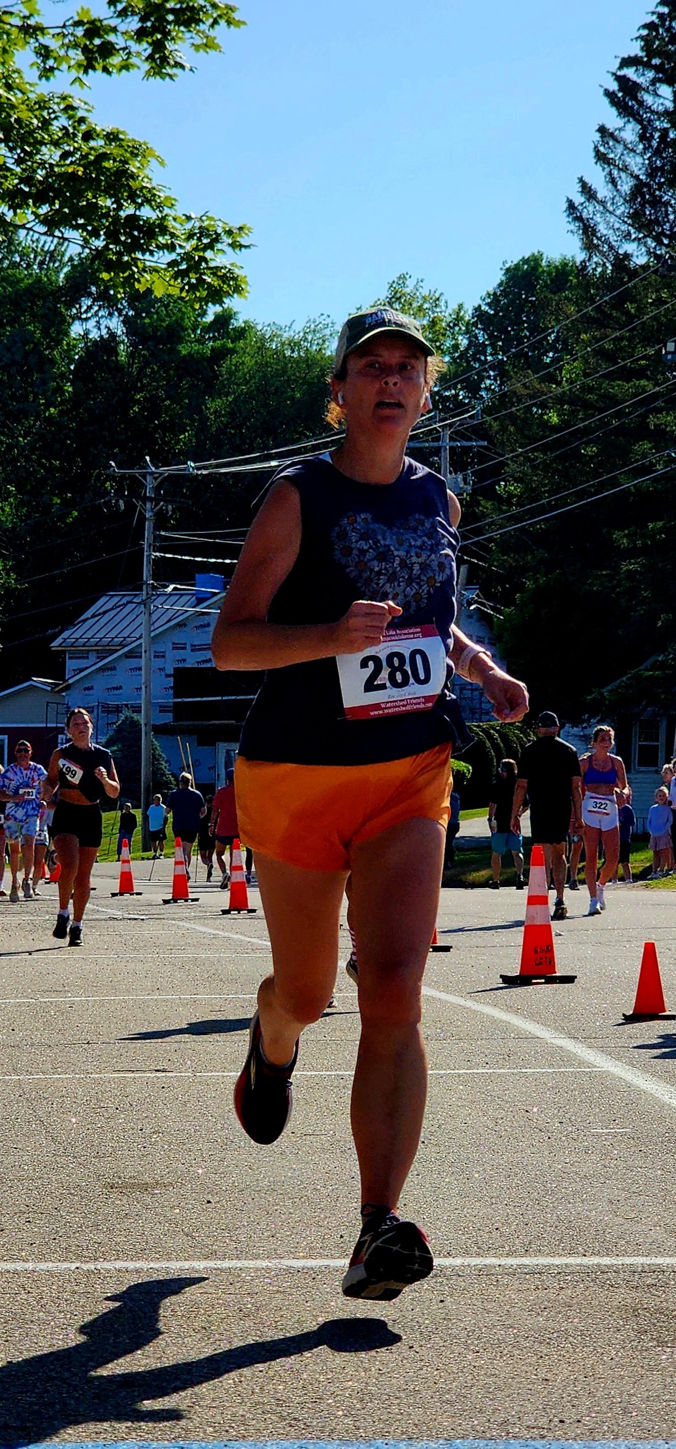 A woman wearing a black tank top and orange shorts running