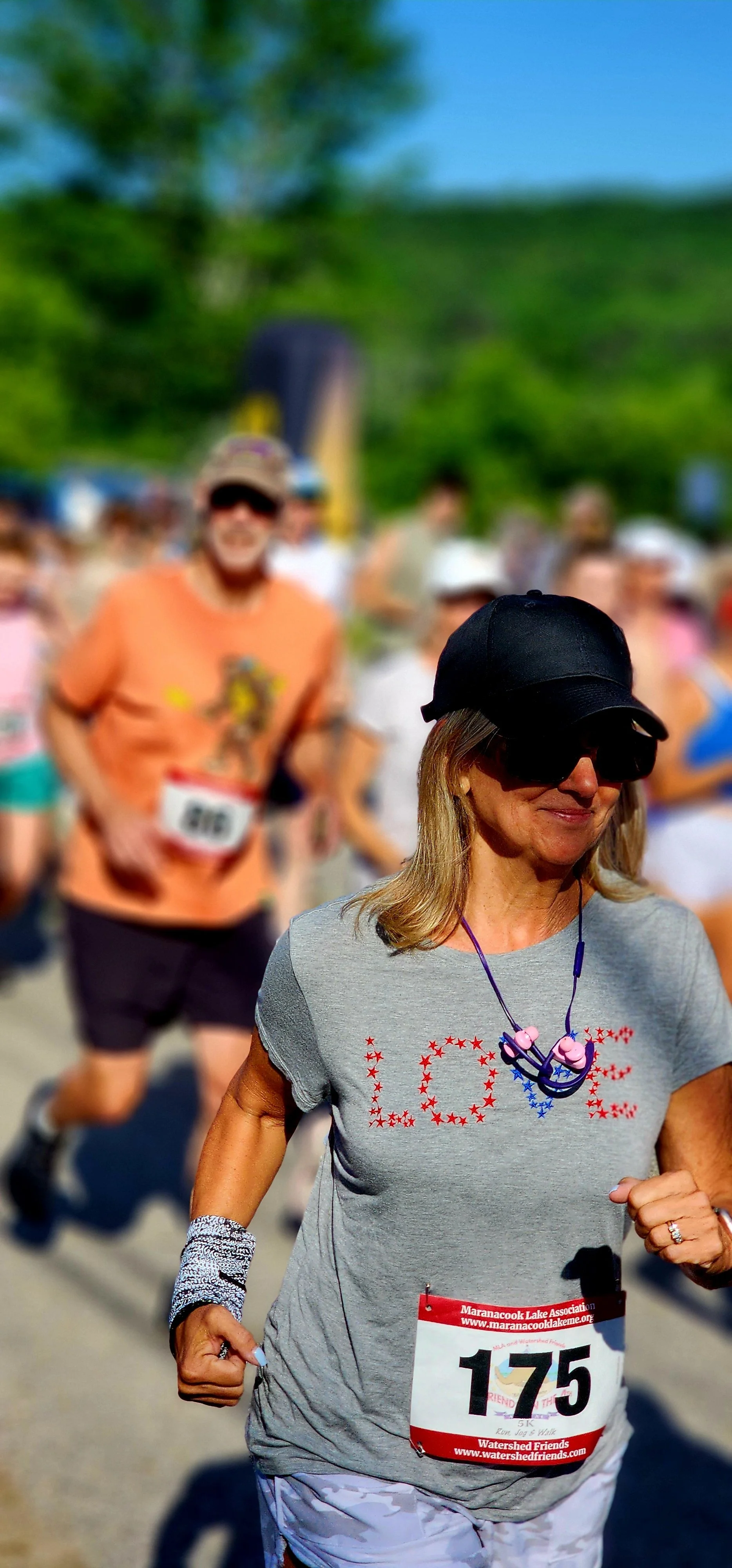 A woman in a grey t-shirt that says "love" running, with a crowd behind her