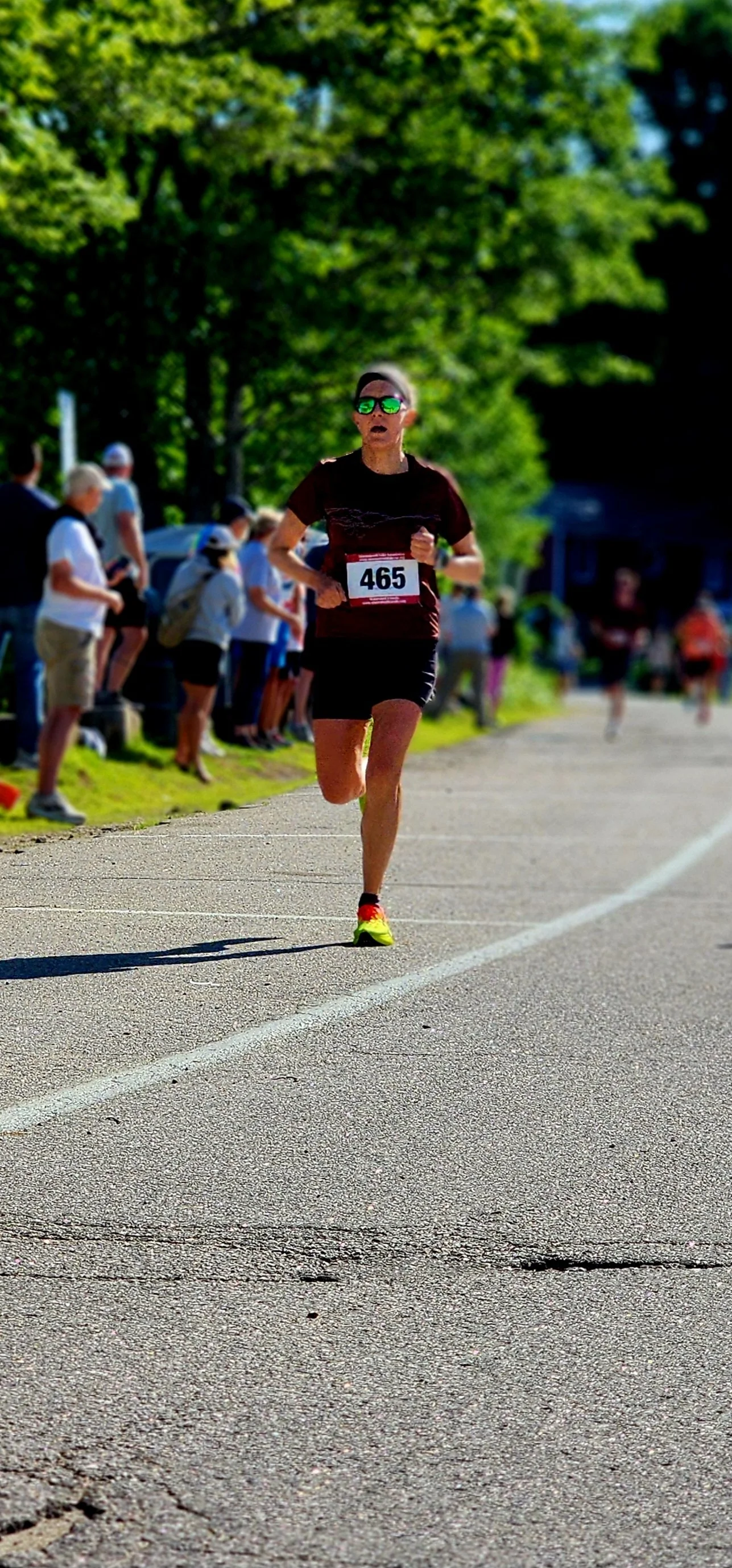 A man wearing a black t-shirt and shorts running with a crowd standing in the background