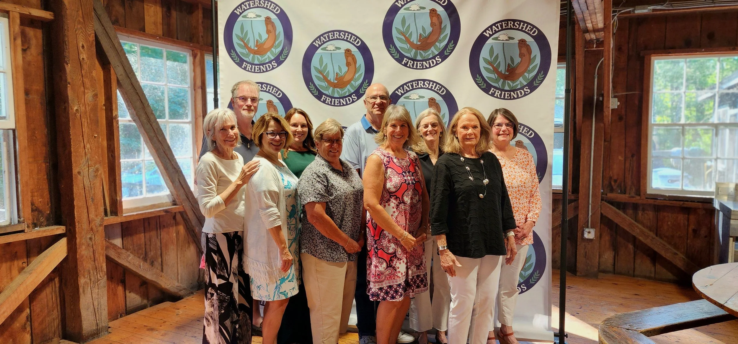 Ten people standing in front of a backdrop with the Watershed Friends logo