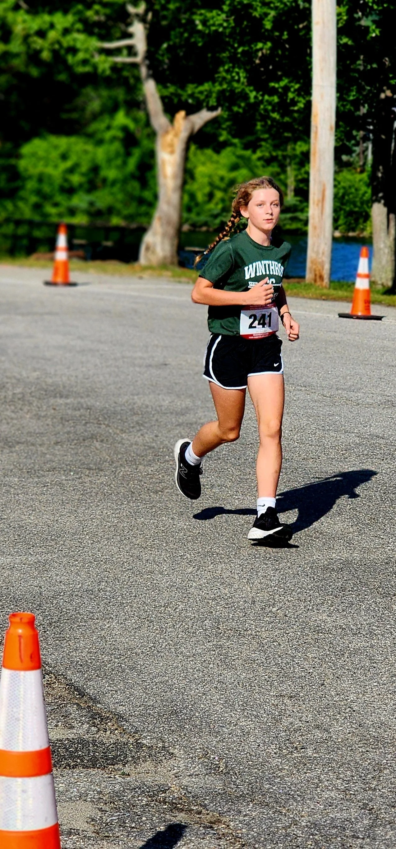 A girl wearing a green t-shirt and shorts running
