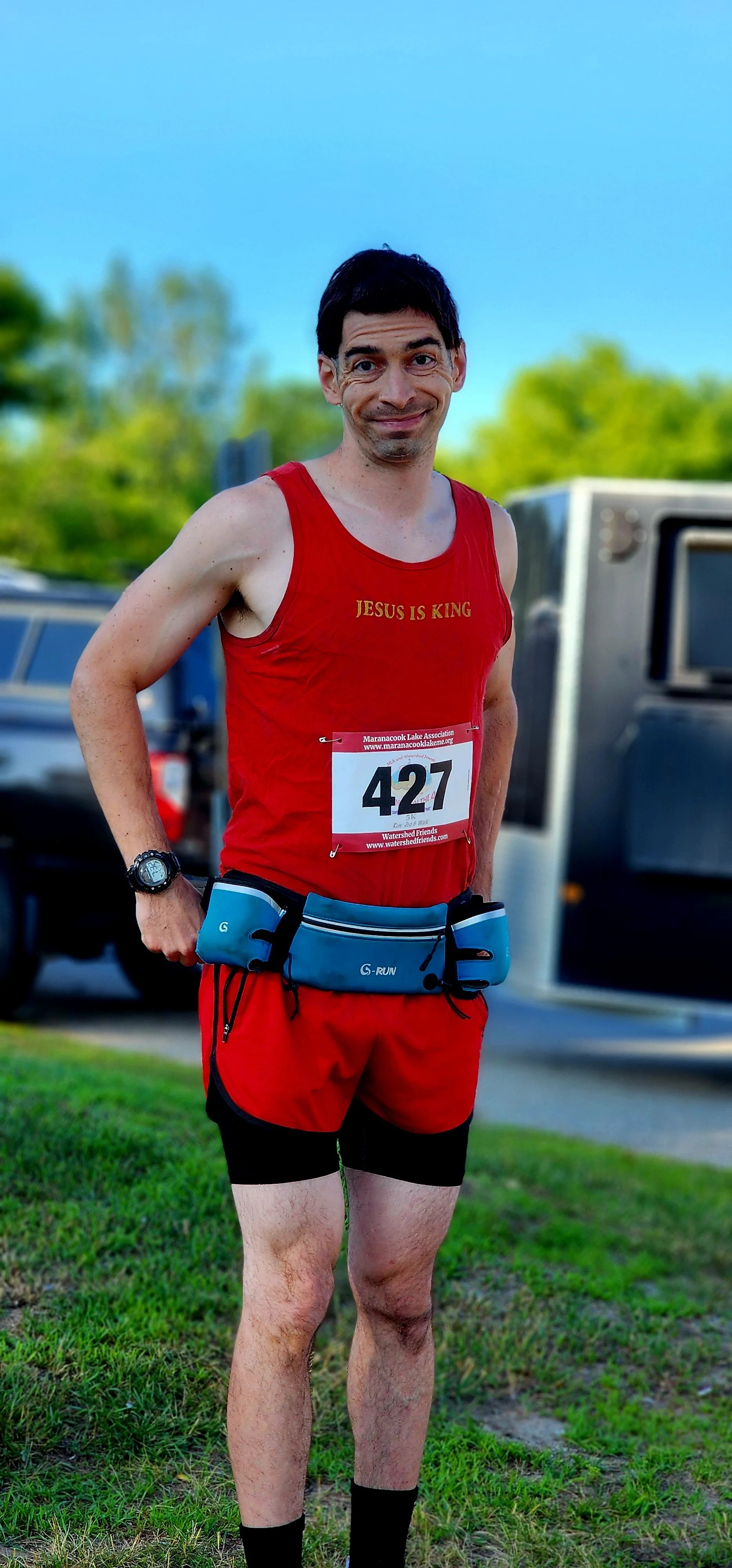 A man wearing a red tank top and red short, smiling at the camera