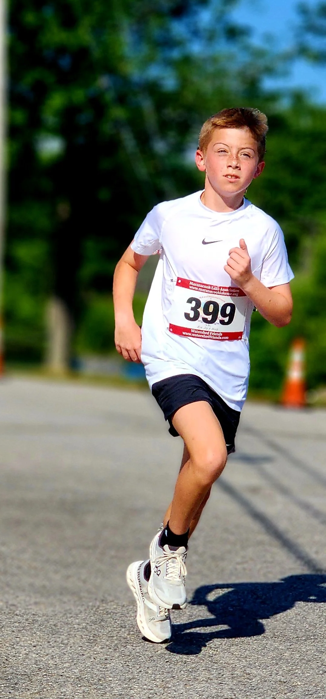 A boy in a white t-shirt and black shorts running