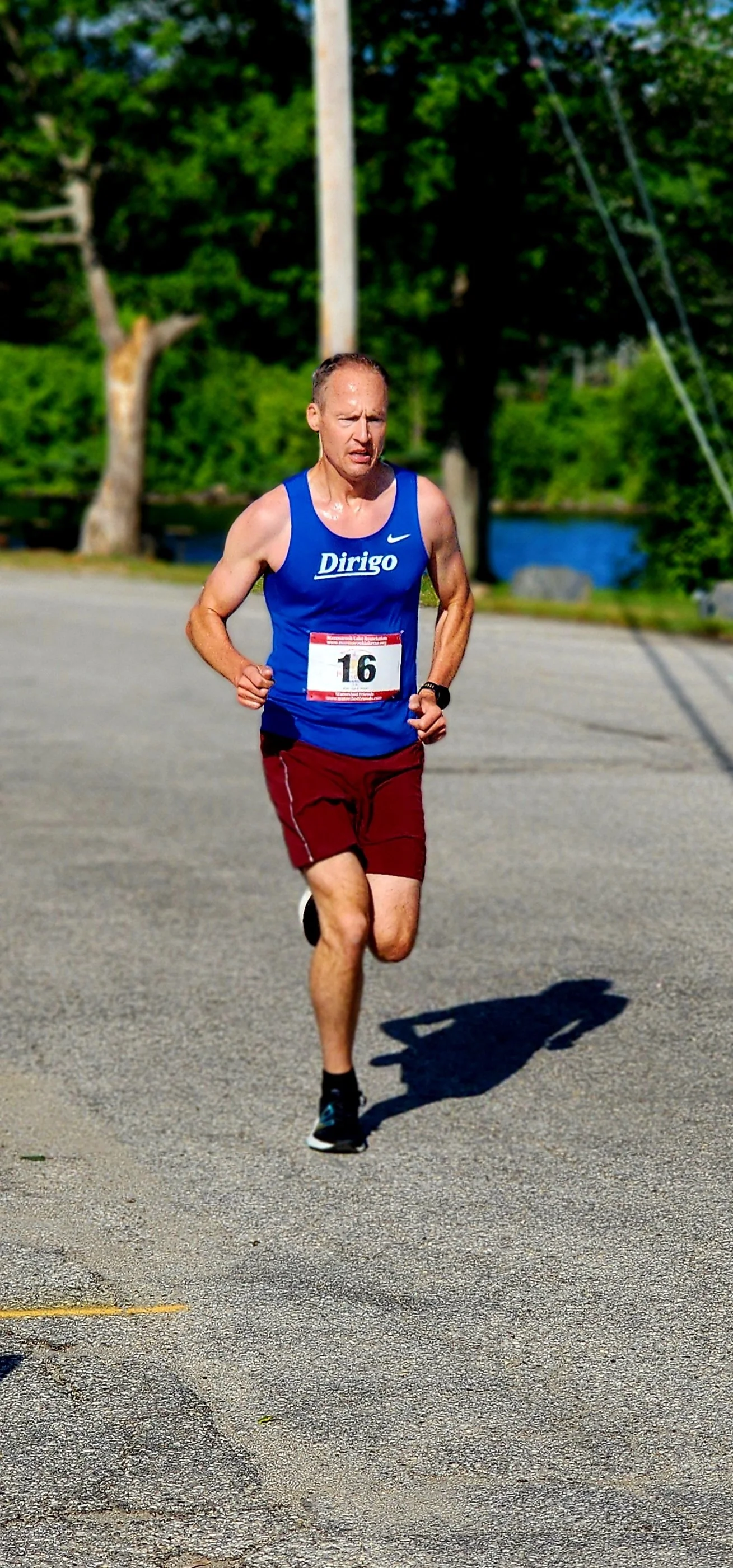 A man wearing a blue tank top and maroon shorts