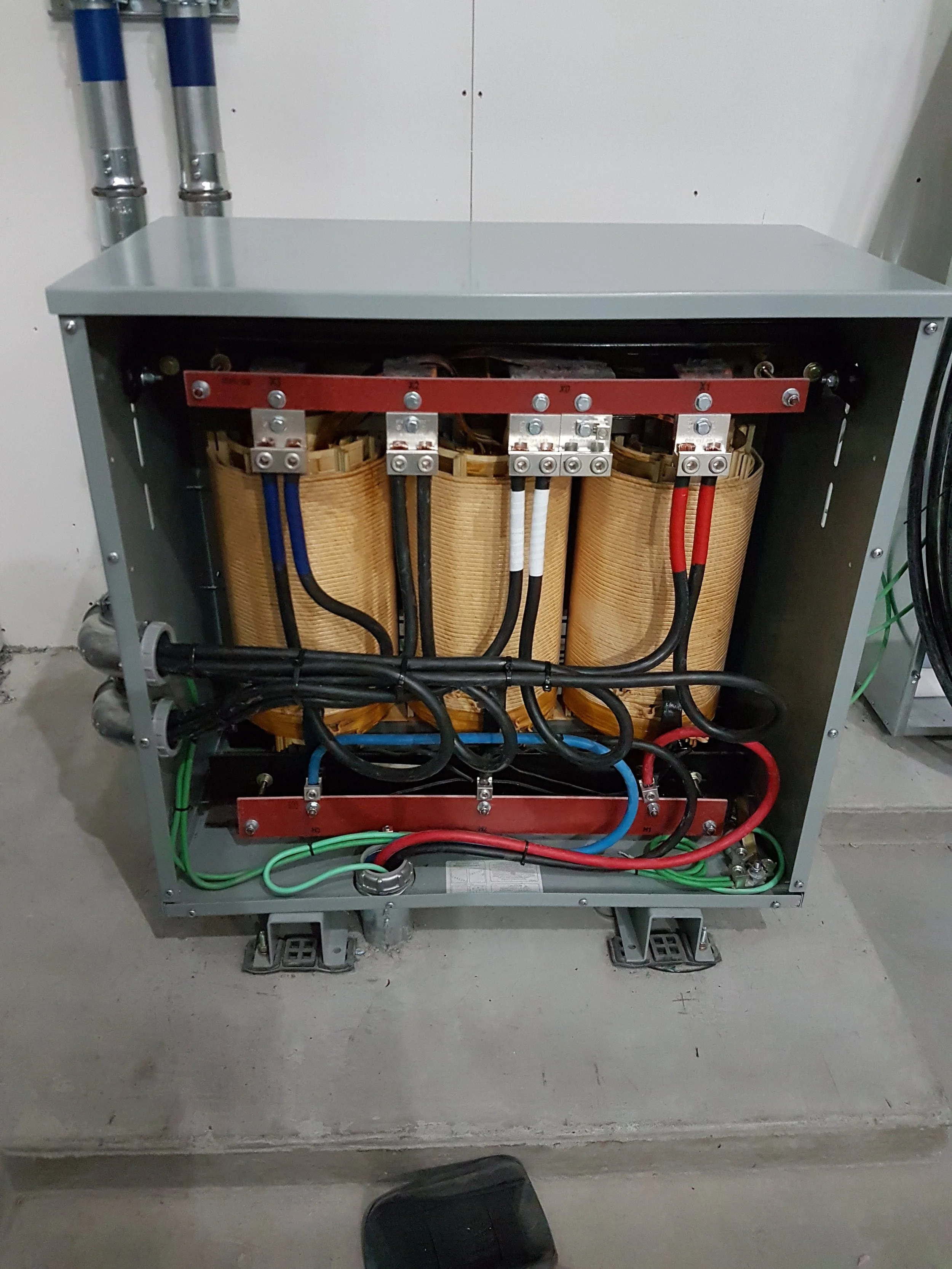 Open electrical transformer with insulated coils and wiring inside a metal enclosure.