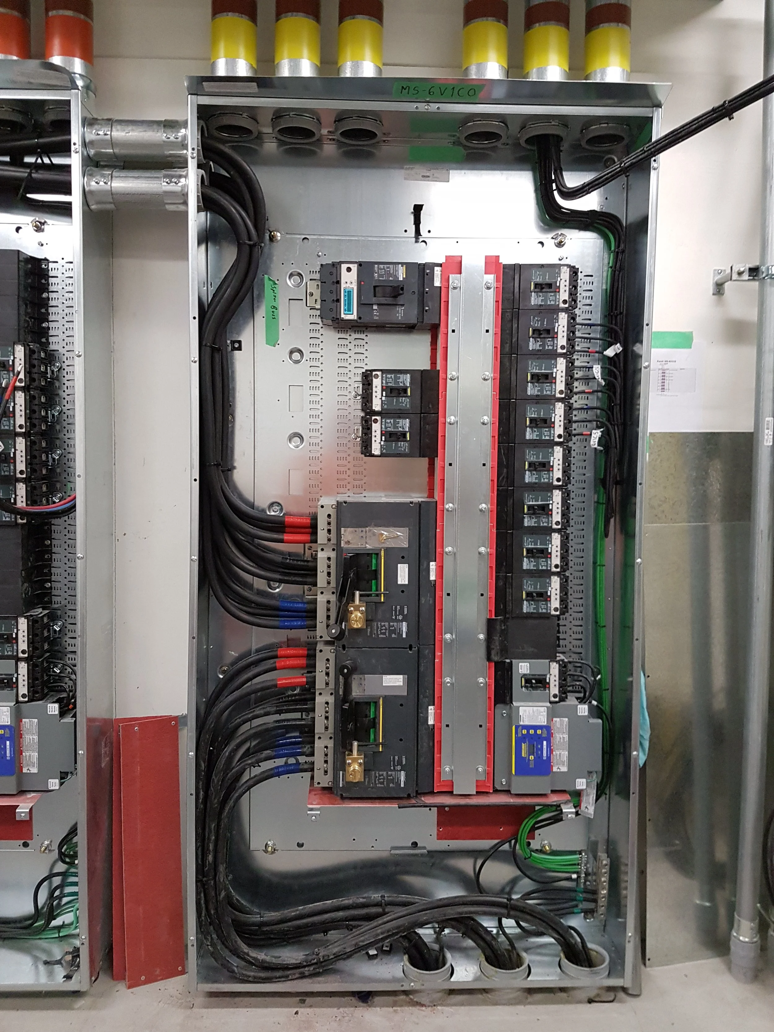 Electrical control panel with circuit breakers, wiring, and colored labels.