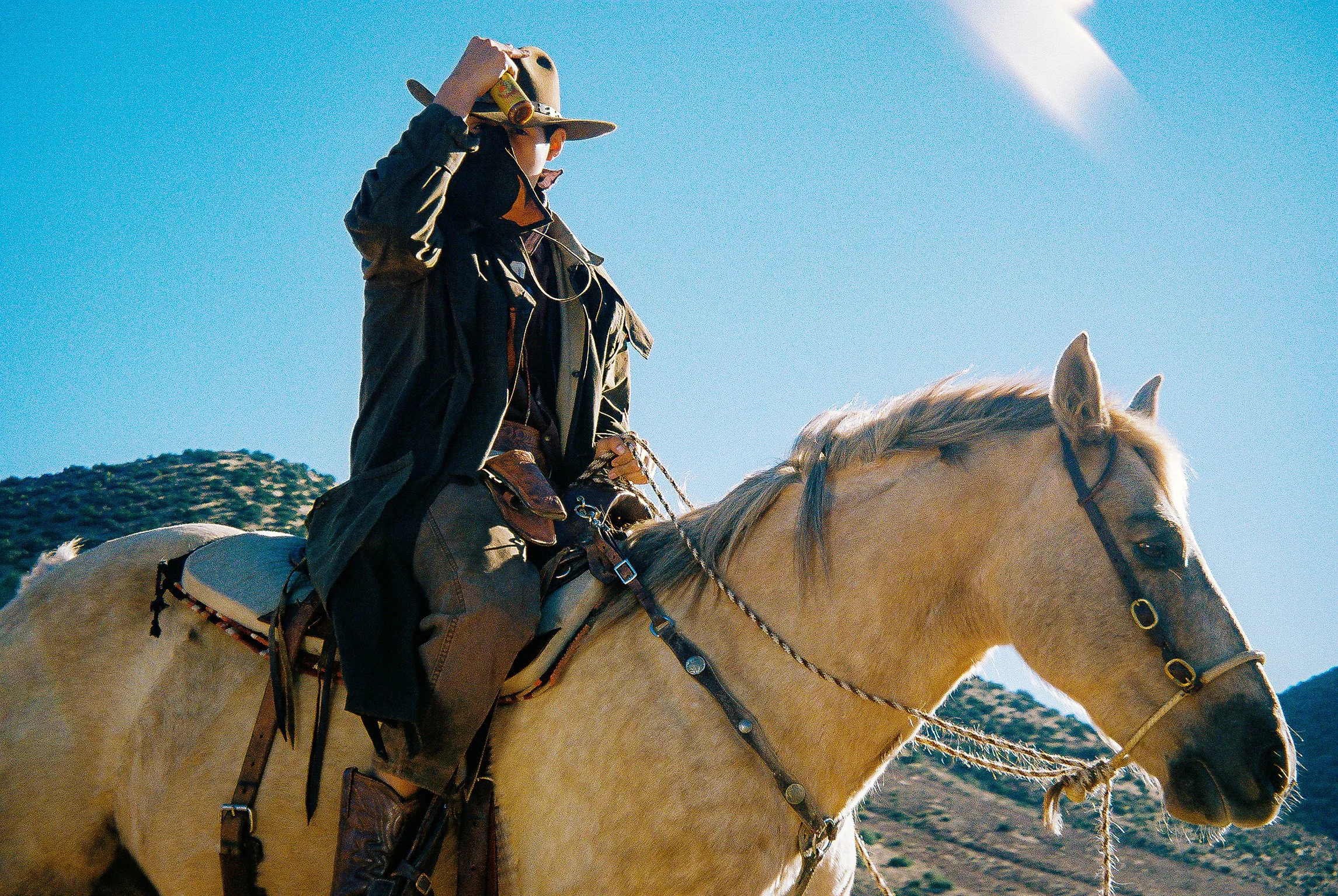 A person riding a white horse in a mountainous area with clear blue sky.