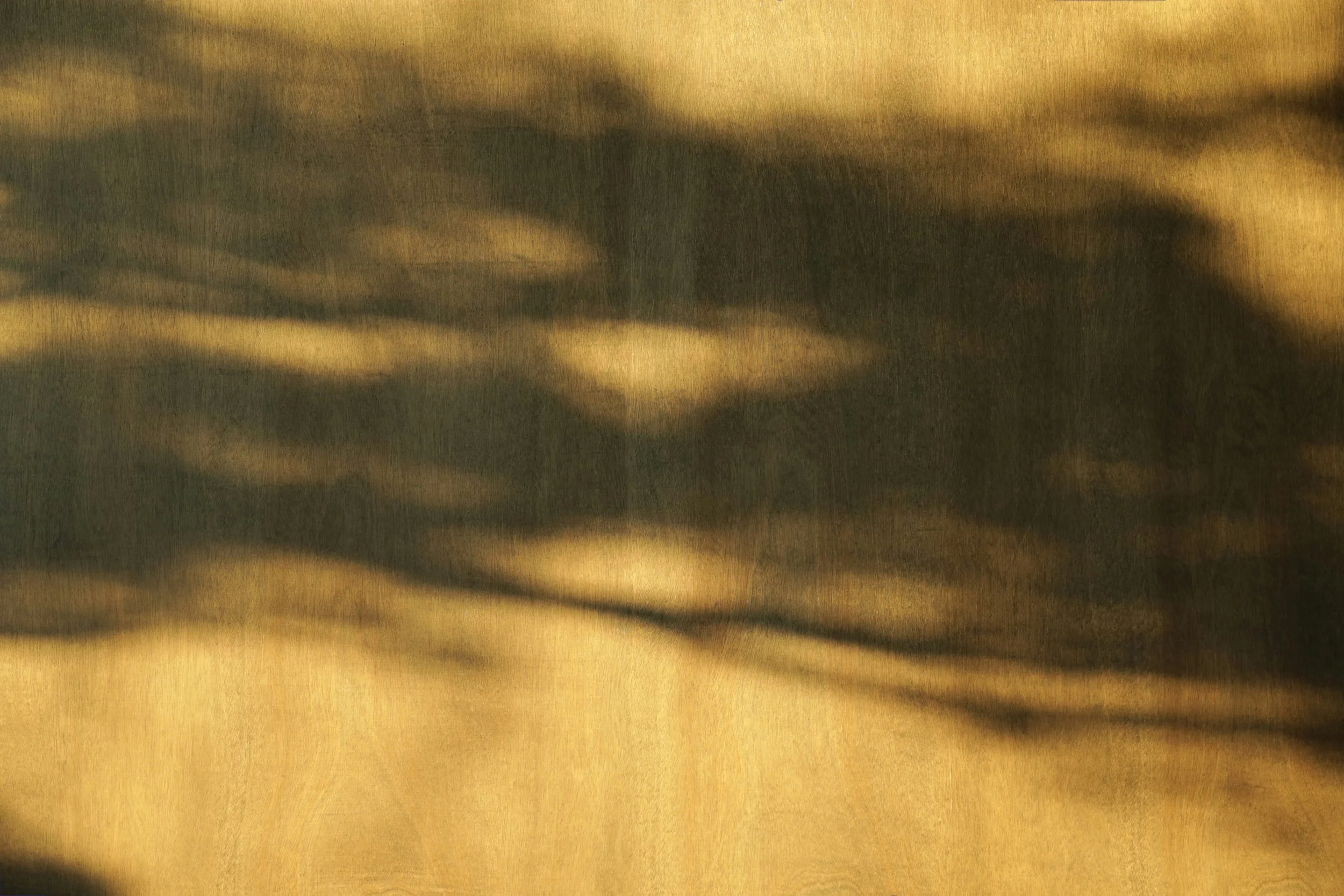 Close-up of golden fabric with dark shadows and uneven folds.