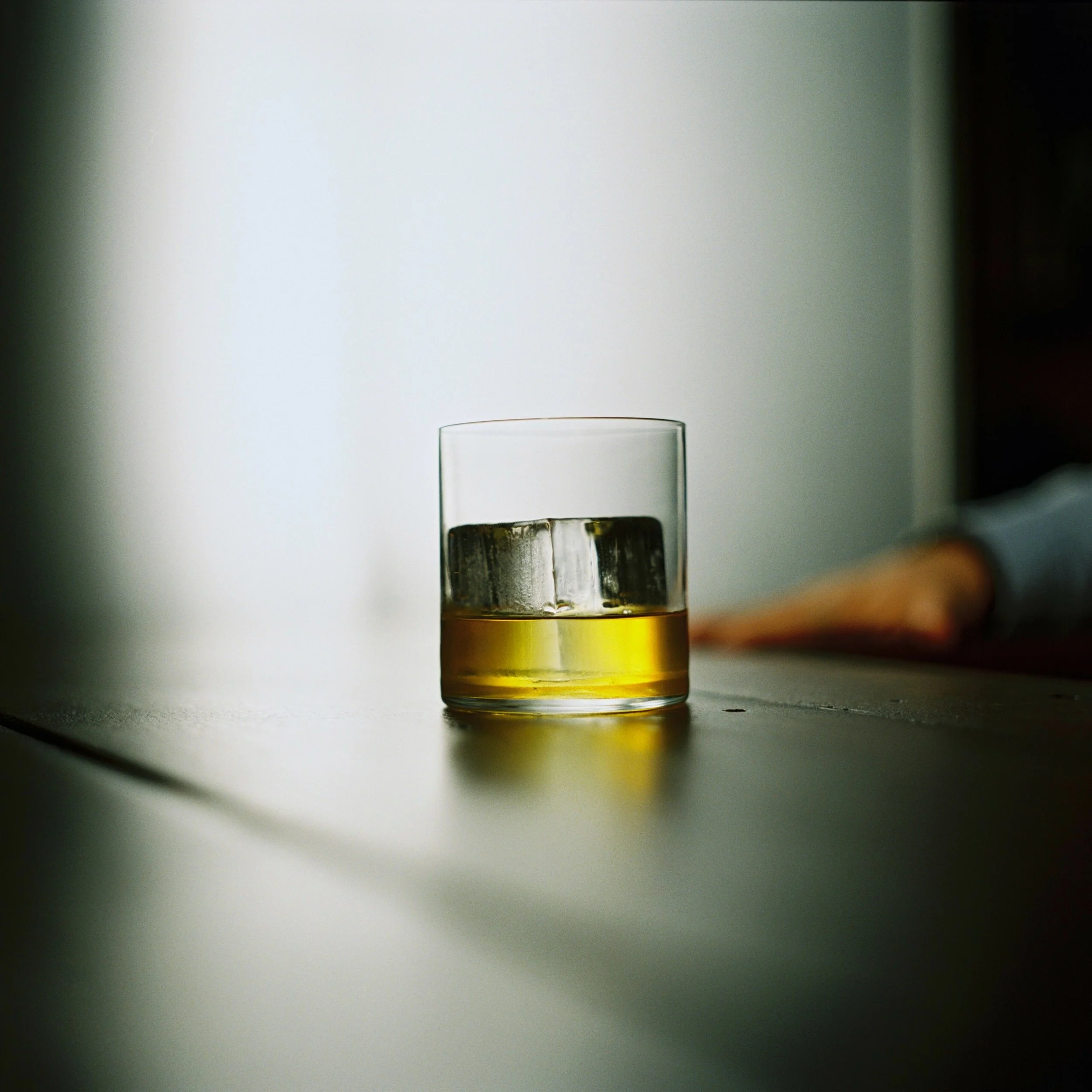 A glass of whiskey with ice on a table.