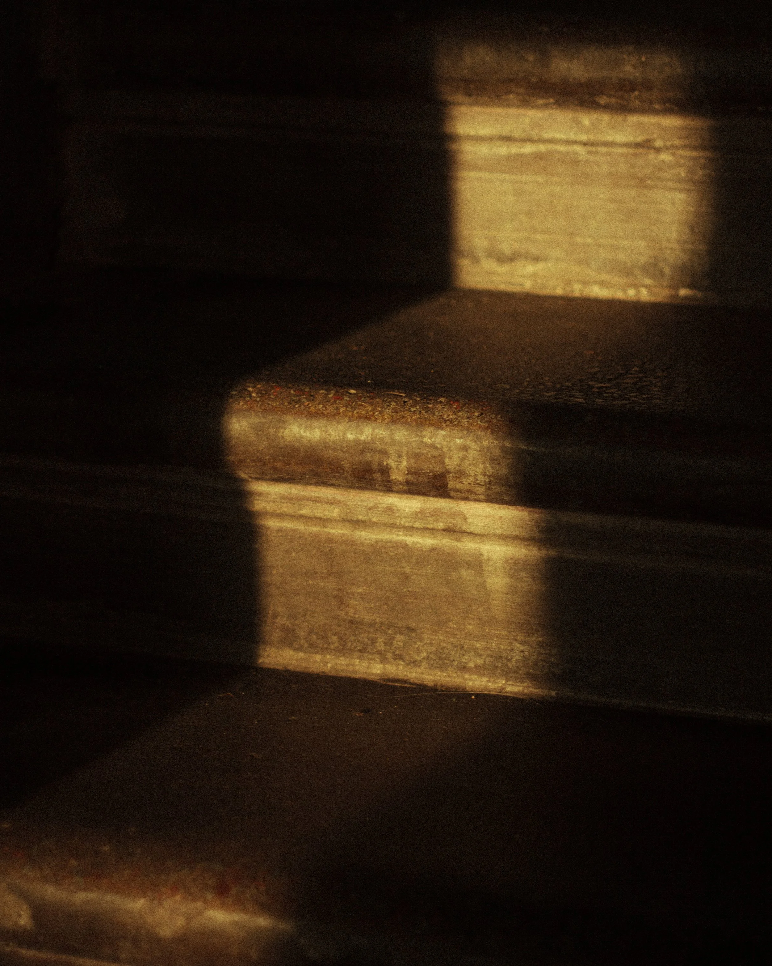 Close-up of a dark surface with a warm, golden light reflecting off it, creating abstract patterns and shadows.