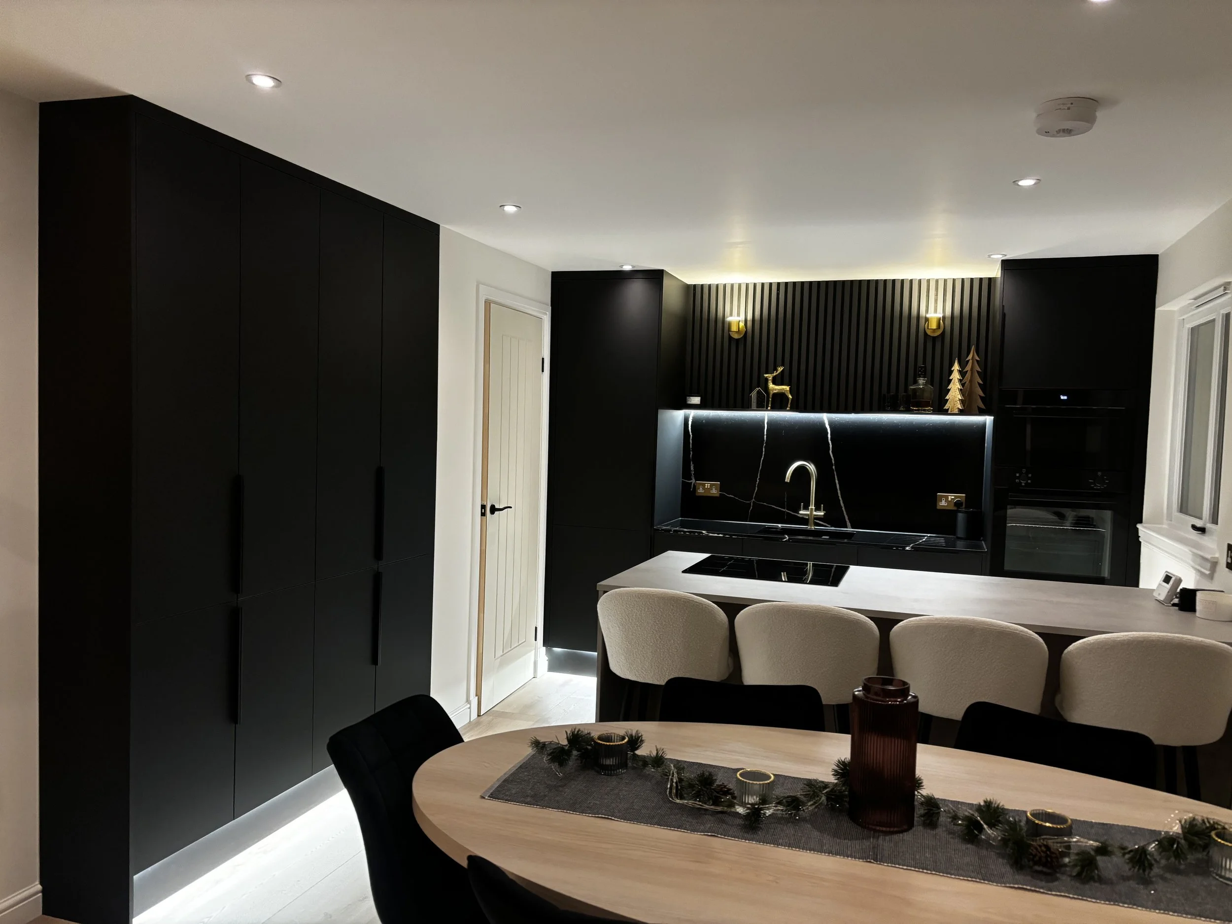 Modern kitchen with black cabinetry, white countertop island, and decorative holiday table centerpiece