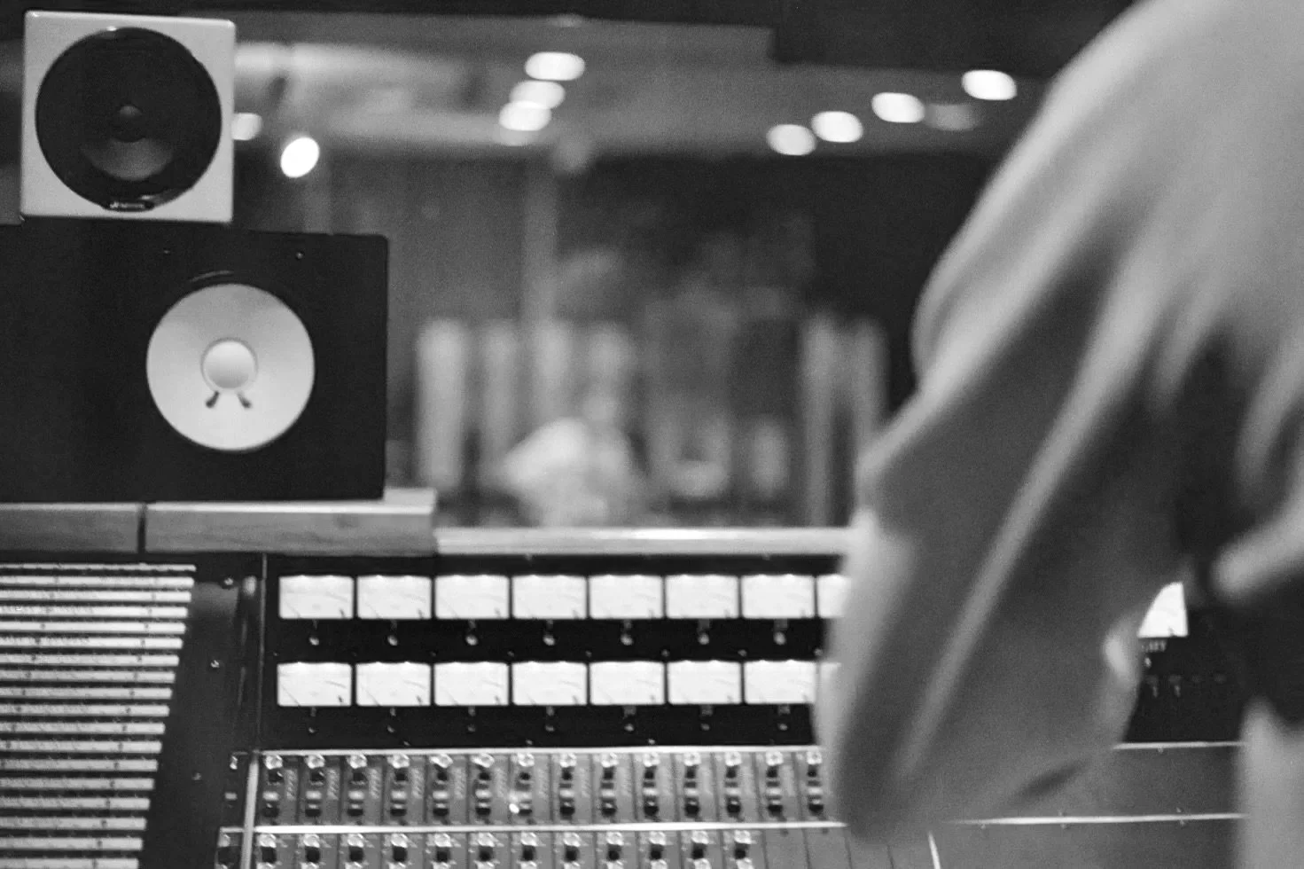 A person working with audio equipment in a recording studio, including a speaker and a mixing console.